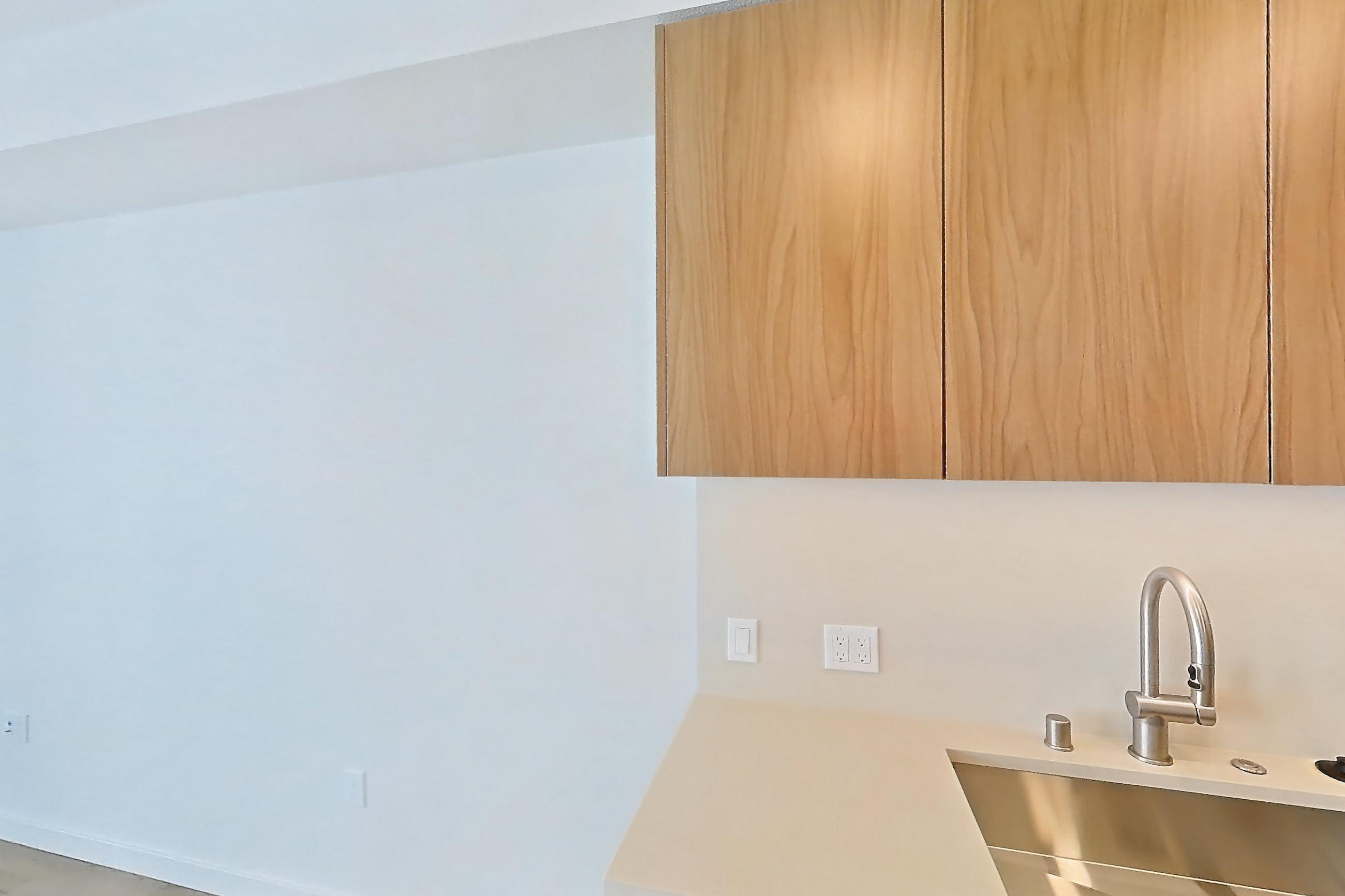 Kitchen with dishwasher, electric range, light countertops, light stone countertops, light wood-finish flooring, oven/range, refrigerator, and stainless steel appliances, Apartment 423 at Rowyn