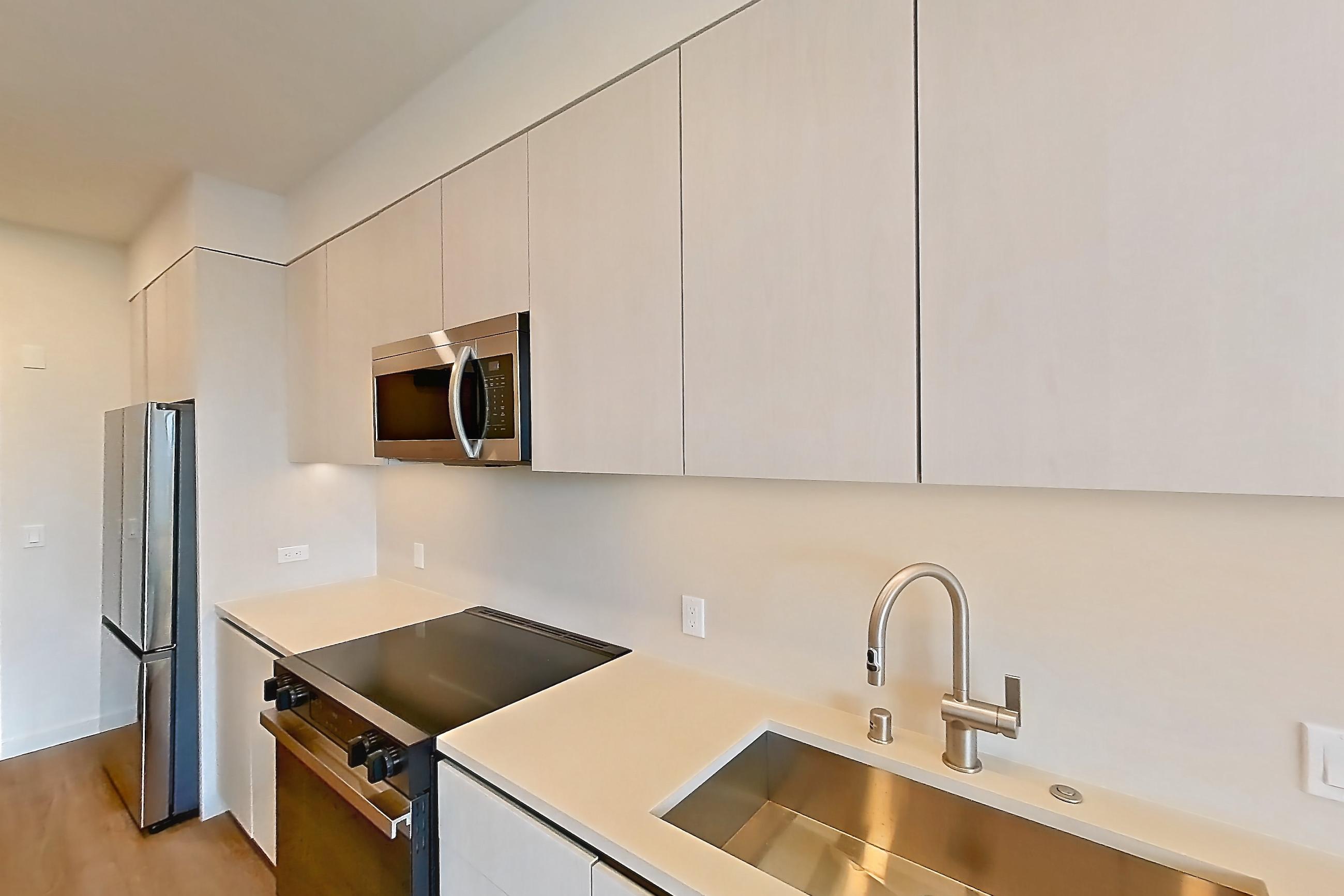 Kitchen with dishwasher, electric range, light countertops, light wood-finish flooring, microwave, oven/range, refrigerator, and stainless steel appliances, Apartment 525 at Rowyn