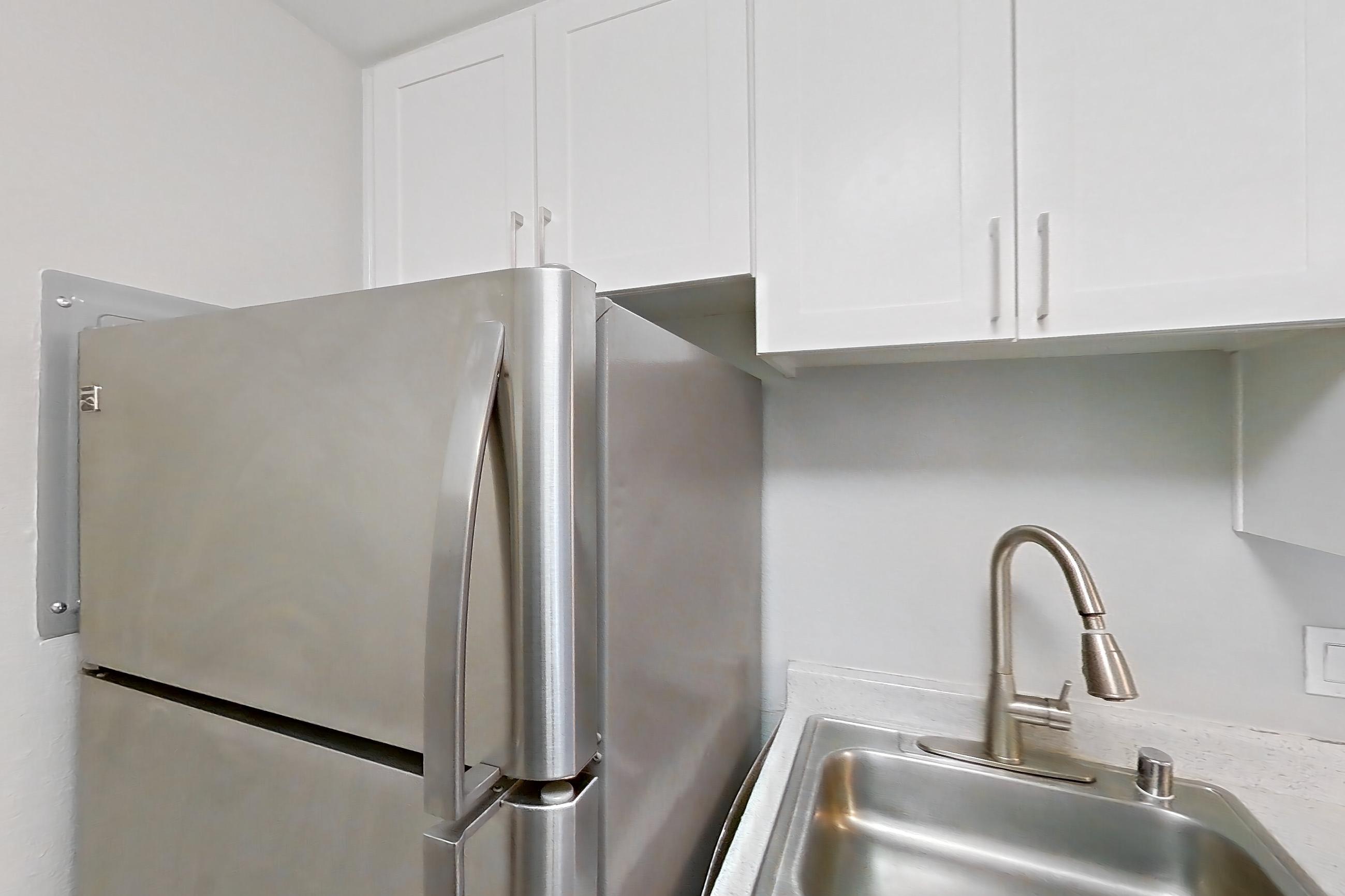 Kitchen with dishwasher, electric range, light countertops, light stone countertops, light wood-finish flooring, oven/range, range hood, refrigerator, and stainless steel appliances, Apartment 06-08 at Avana Rancho Cucamonga