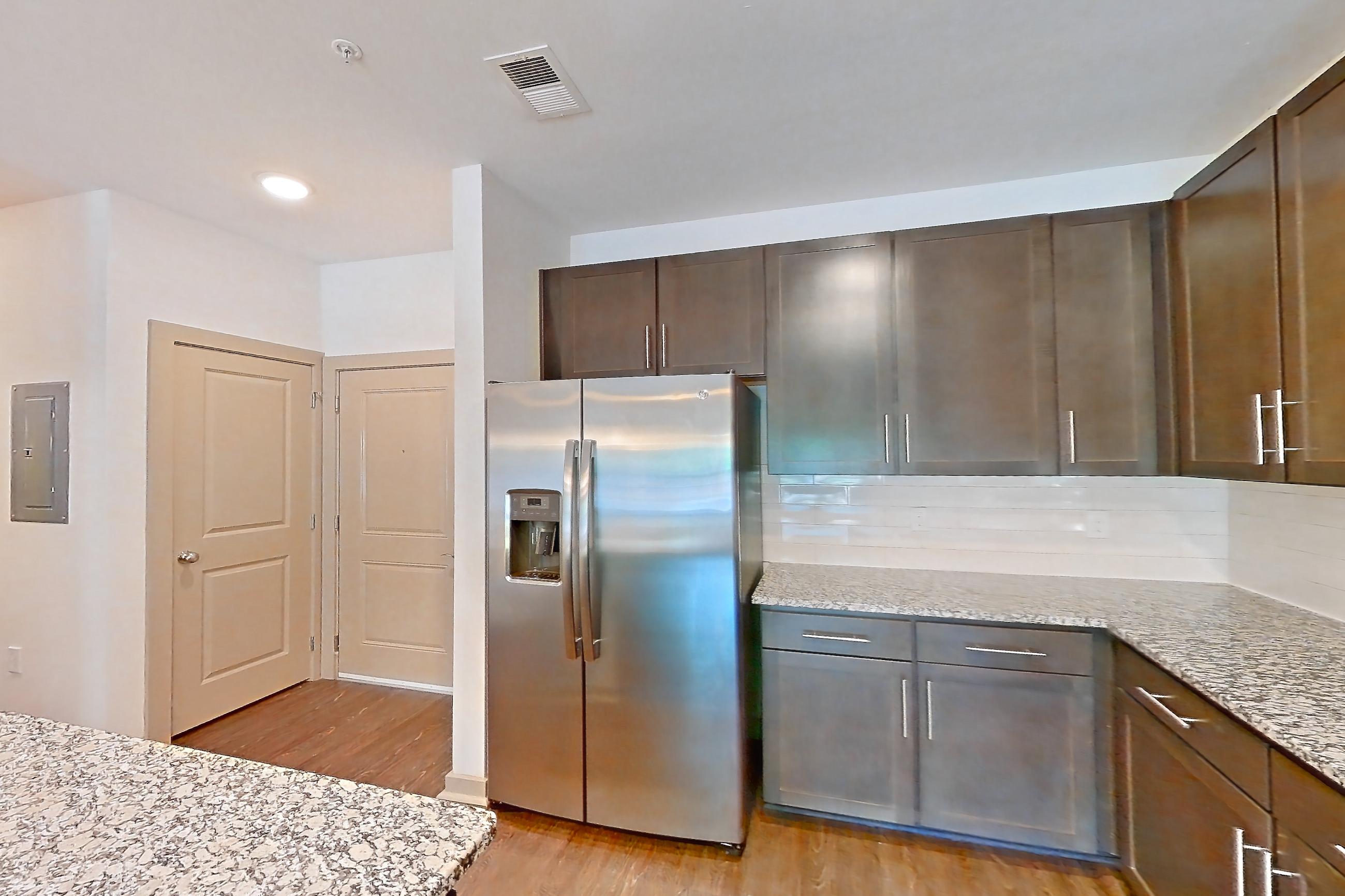 Kitchen with dishwasher, electric range, light stone countertops, light wood-finish flooring, microwave, oven/range, refrigerator, stainless steel appliances, and water & ice dispenser, Apartment 7-206 at Aventine Northshore