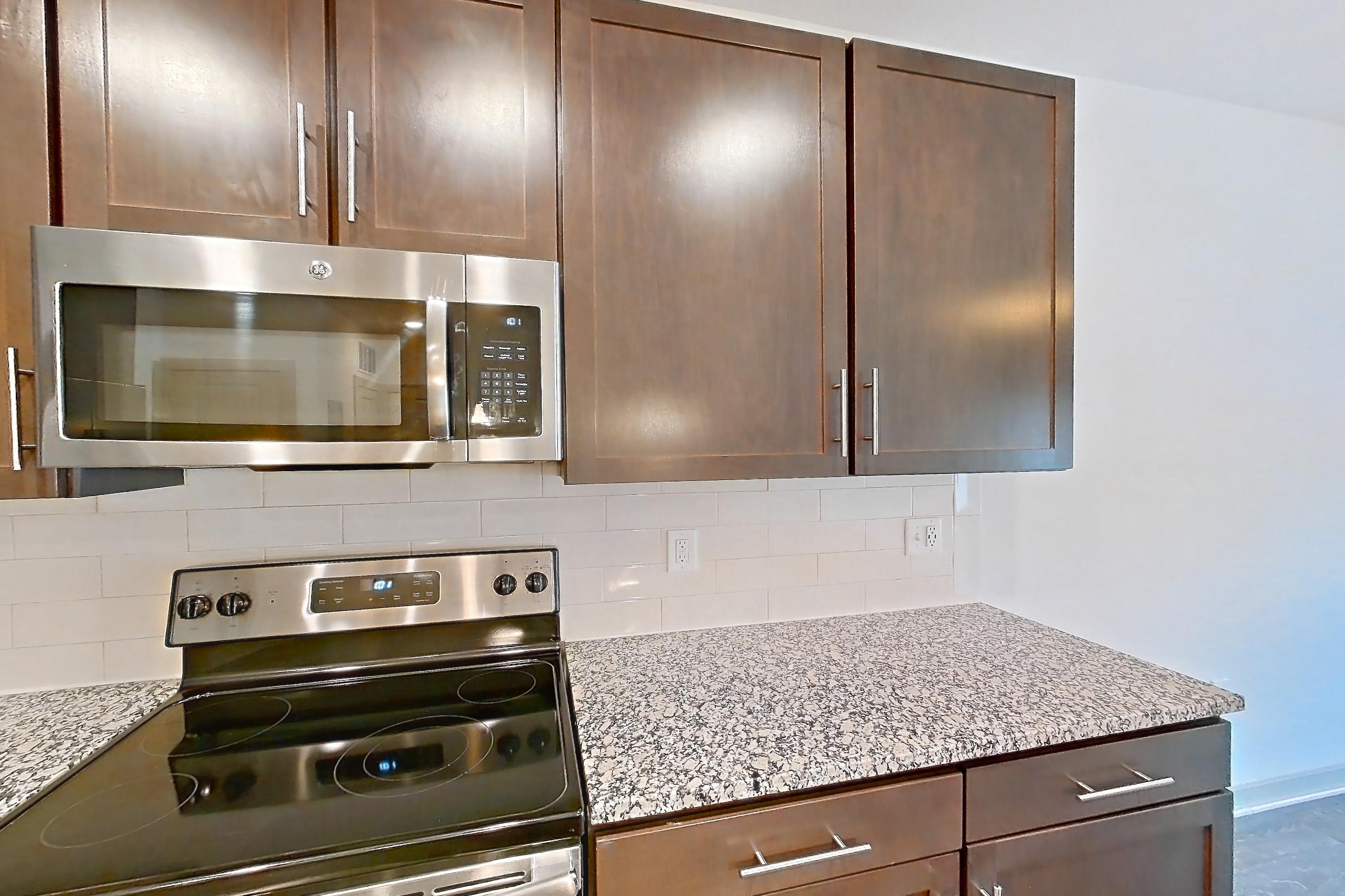 Kitchen with dishwasher, electric range, light stone countertops, light wood-finish flooring, microwave, oven/range, refrigerator, stainless steel appliances, and water & ice dispenser, Apartment 7-206 at Aventine Northshore