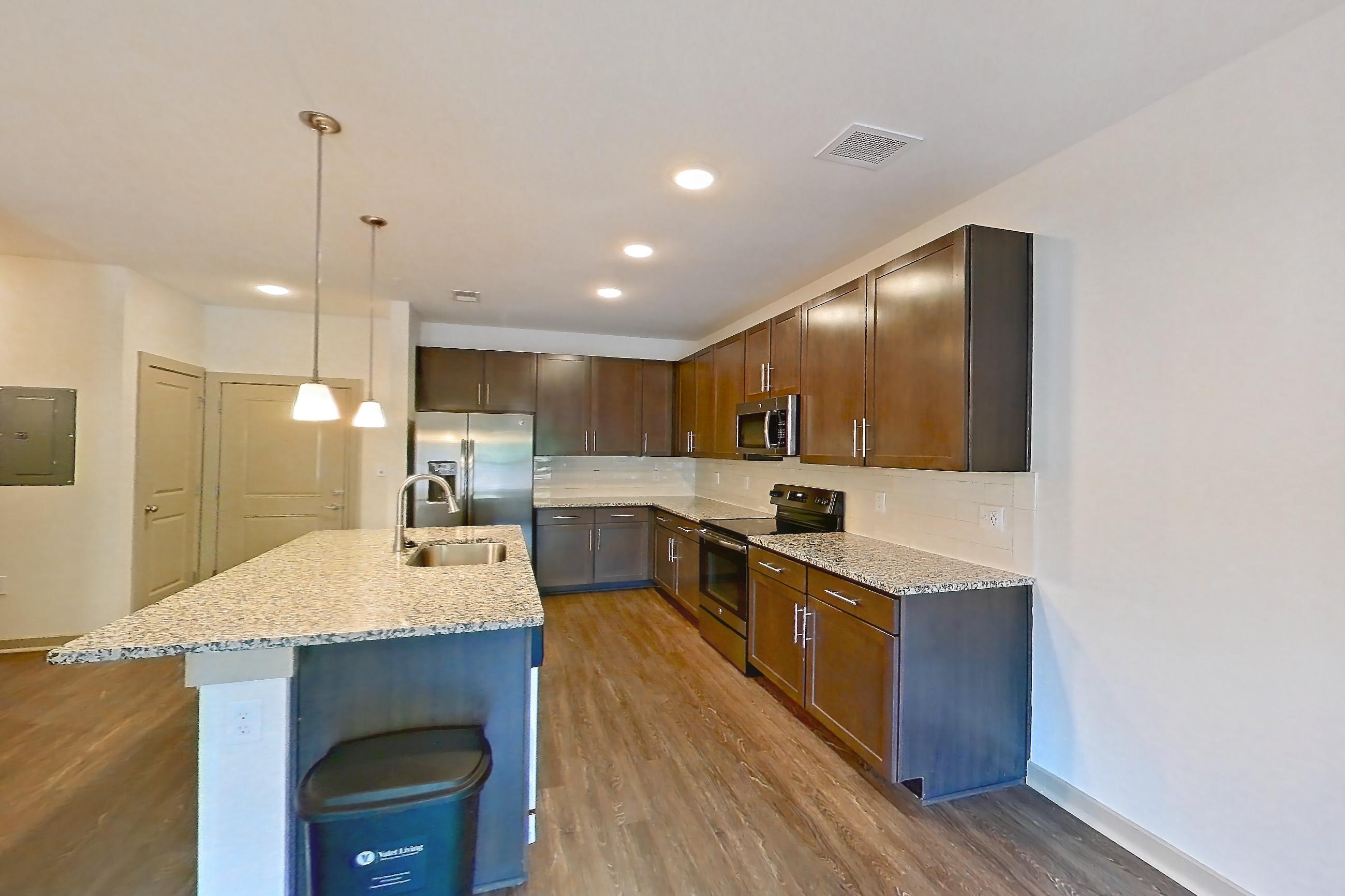 Living room with dark wood-finish flooring, electric range, kitchen island, light stone countertops, oven/range, and stainless steel appliances, Apartment 7-206 at Aventine Northshore