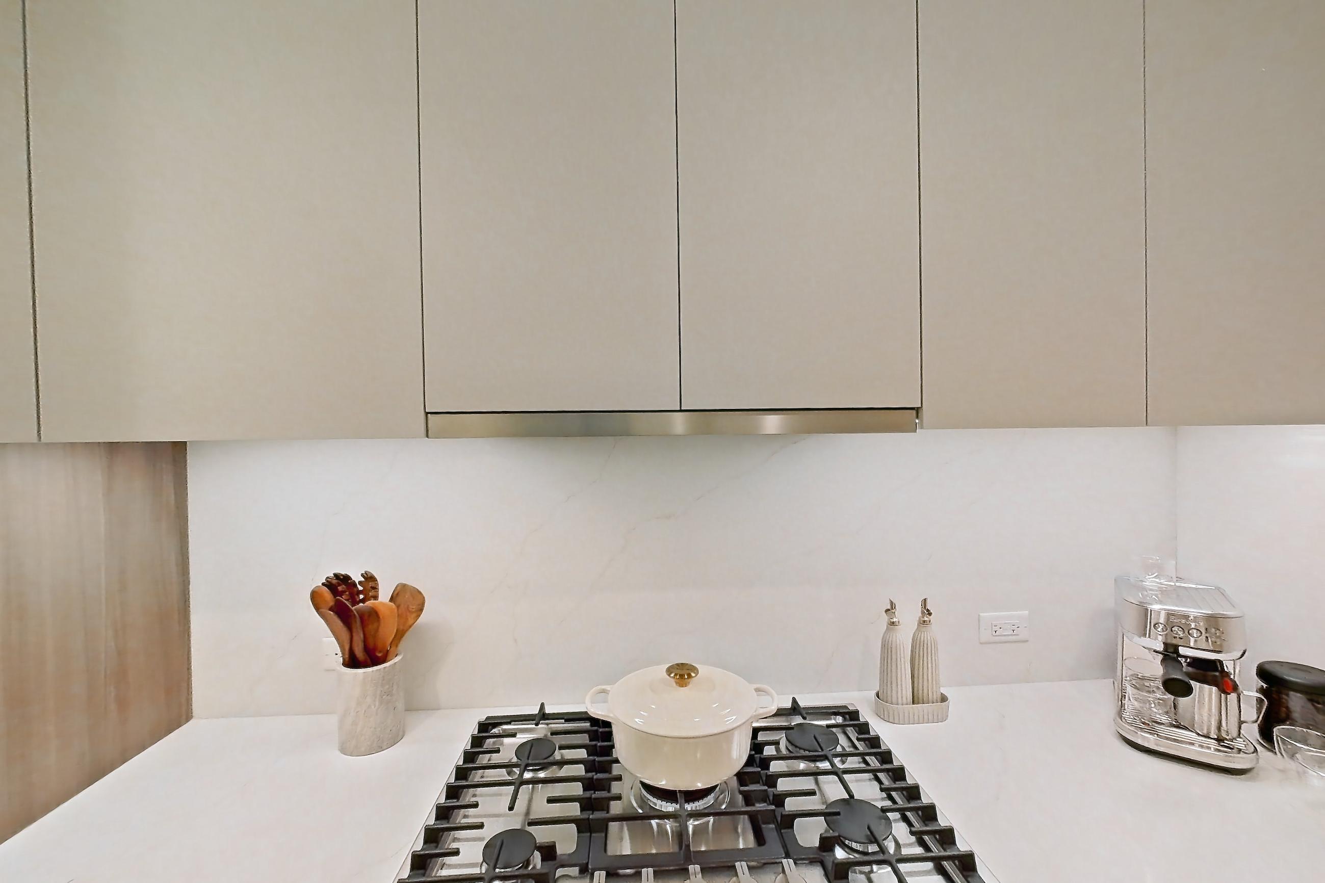Kitchen with cooktop, gas cooktop, light stone countertops, light wood-finish flooring, oven/range, stainless steel appliances, white appliances, and wood-finish flooring, Apartment 03F at Maison 78