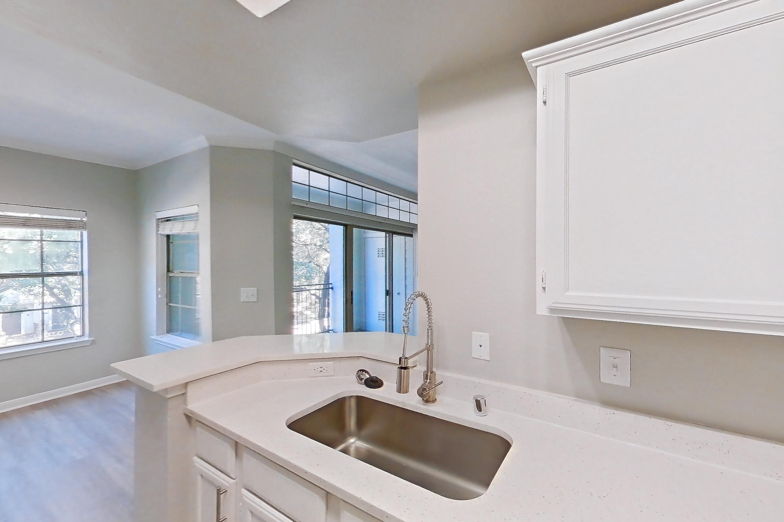 Kitchen with dishwasher, electric range, light countertops, light stone countertops, light wood-finish flooring, microwave, oven/range, refrigerator, and stainless steel appliances, Unit 307 at Riviera at West Village