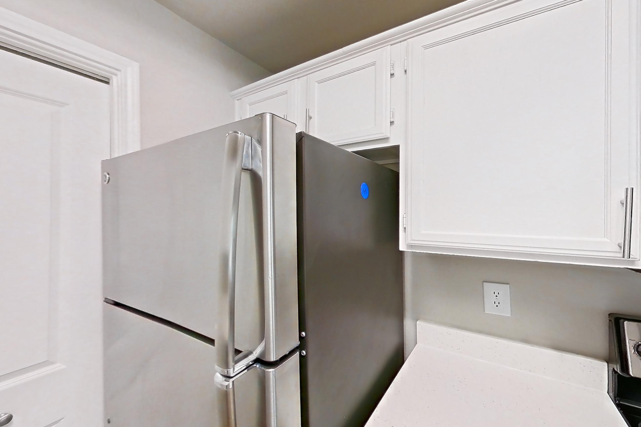 Kitchen with dishwasher, electric range, light countertops, light stone countertops, light wood-finish flooring, microwave, oven/range, refrigerator, and stainless steel appliances, Unit 307 at Riviera at West Village