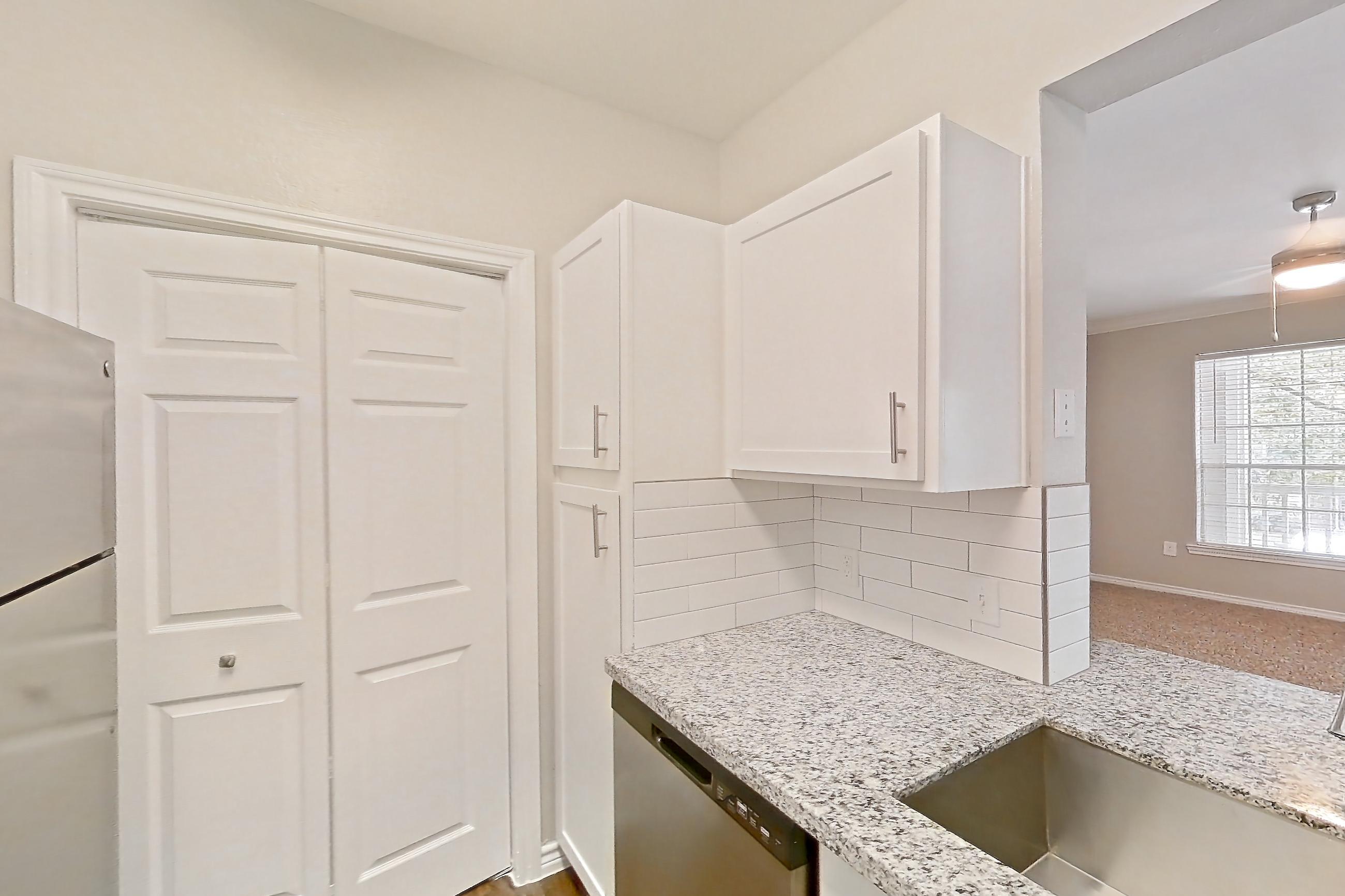 Kitchen with dark wood-finish flooring, dishwasher, electric range, light countertops, light stone countertops, oven/range, refrigerator, and stainless steel appliances, Apartment 0722 at Reserve at Kingwood