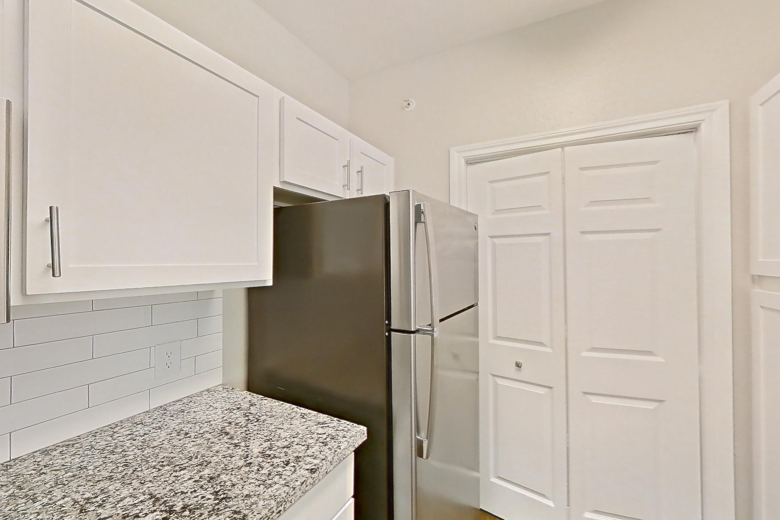 Kitchen with dark wood-finish flooring, dishwasher, electric range, light countertops, light stone countertops, oven/range, refrigerator, and stainless steel appliances, Apartment 0722 at Reserve at Kingwood