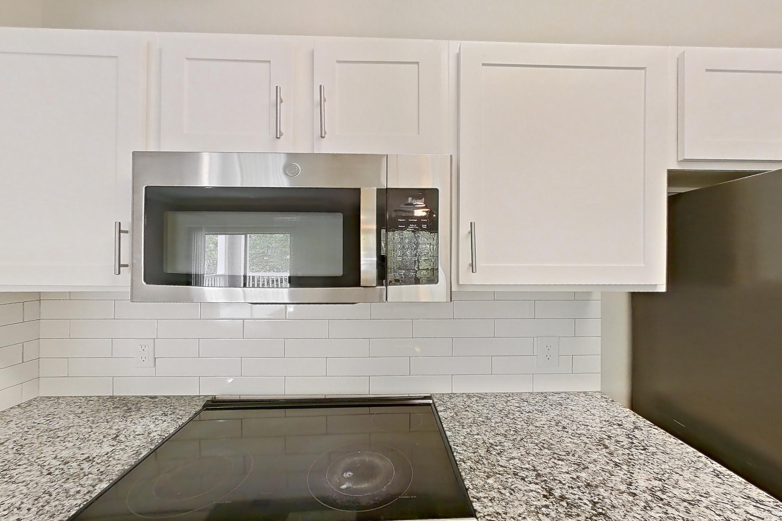 Kitchen with dark wood-finish flooring, dishwasher, electric range, light countertops, light stone countertops, oven/range, refrigerator, and stainless steel appliances, Apartment 0722 at Reserve at Kingwood