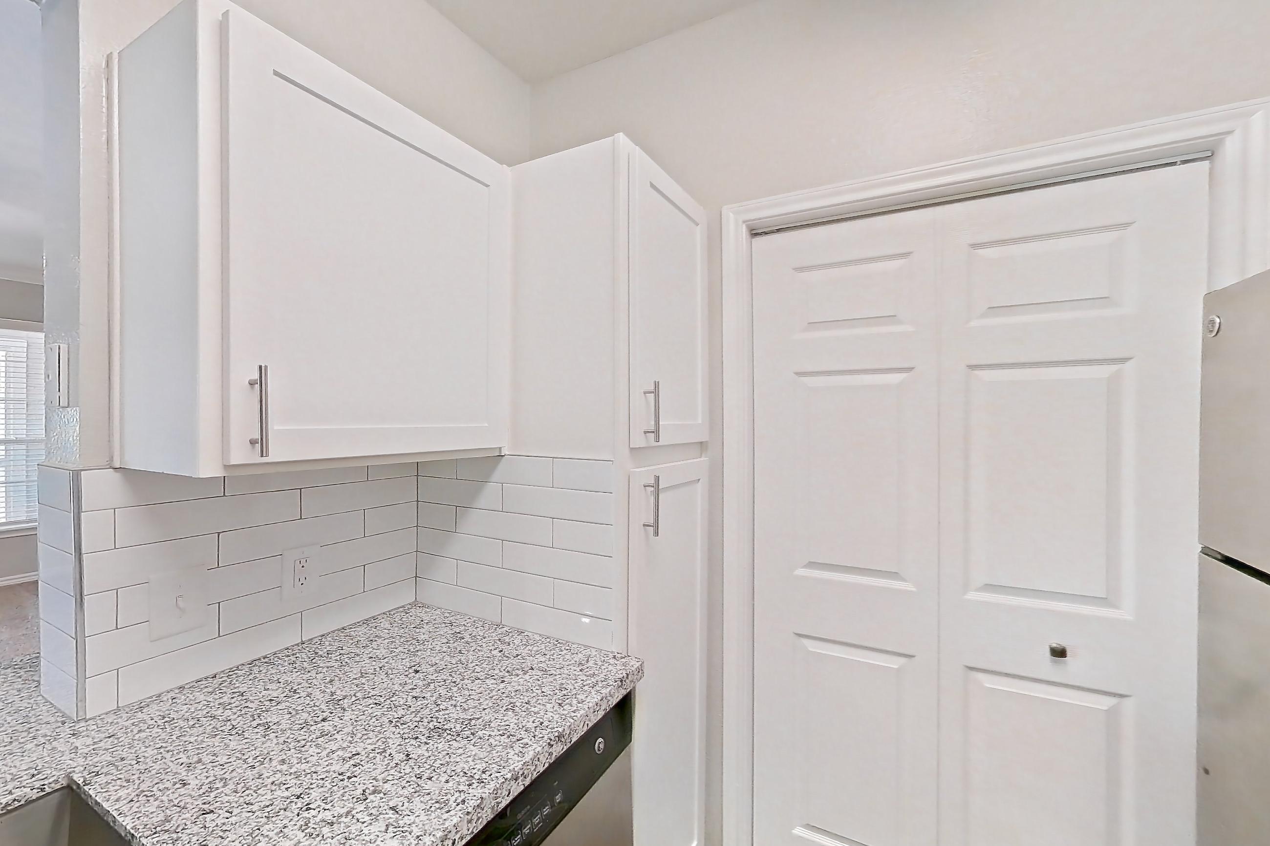 Kitchen with dark wood-finish flooring, dishwasher, electric range, light carpet, light countertops, light stone countertops, light wood-finish flooring, oven/range, refrigerator, stainless steel appliances, and wood-finish flooring, Apartment 0737 at Reserve at Kingwood