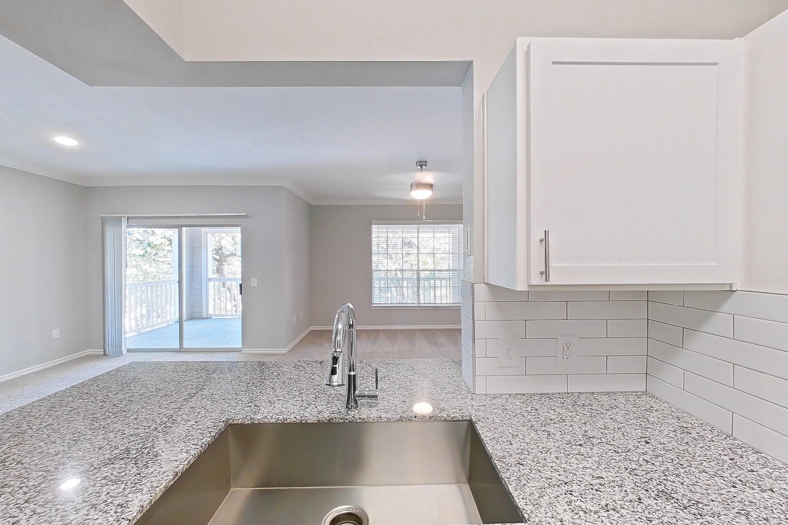 Kitchen with dark wood-finish flooring, dishwasher, electric range, light carpet, light countertops, light stone countertops, light wood-finish flooring, oven/range, refrigerator, stainless steel appliances, and wood-finish flooring, Apartment 0737 at Reserve at Kingwood