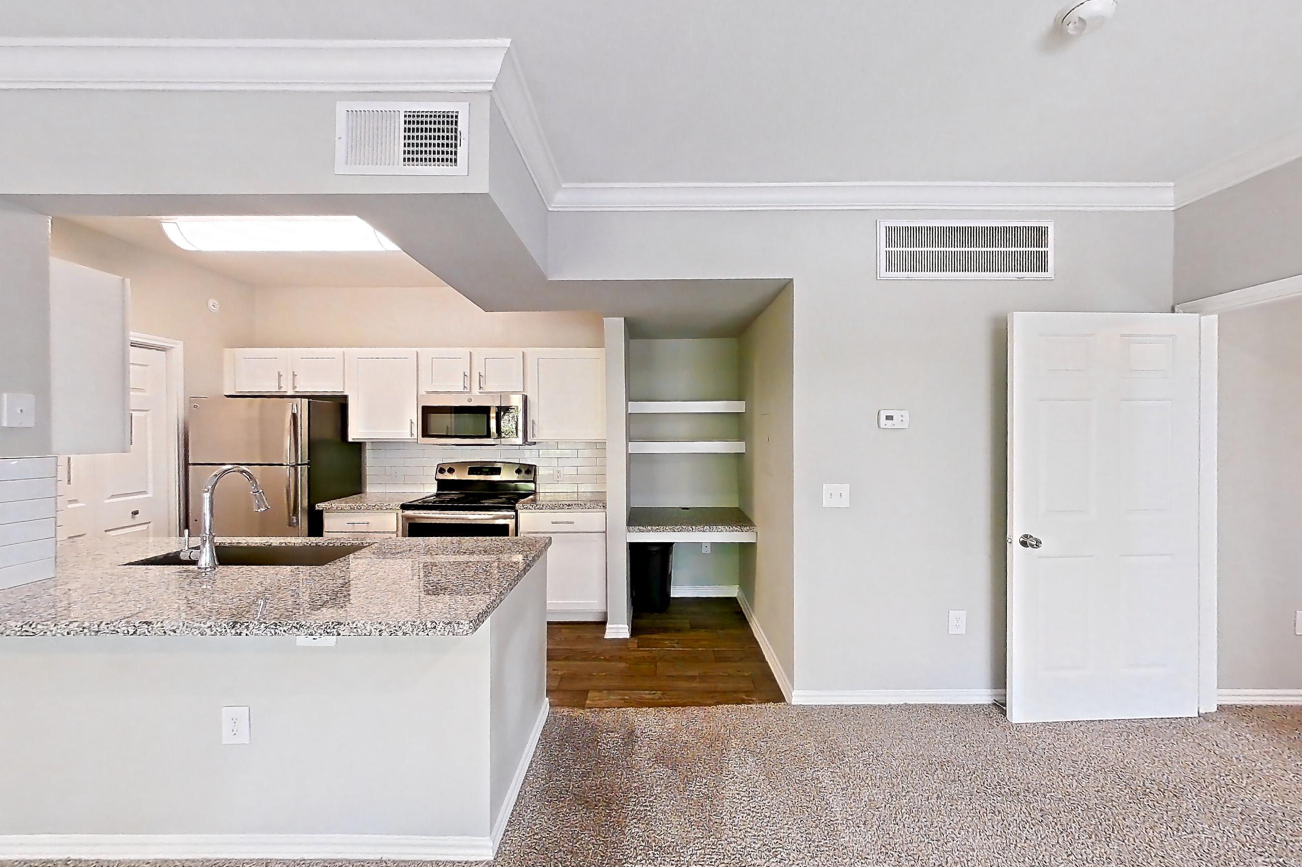 Living room with dark carpet, electric range, kitchen island, light stone countertops, oven/range, refrigerator, and stainless steel appliances, Apartment 0737 at Reserve at Kingwood