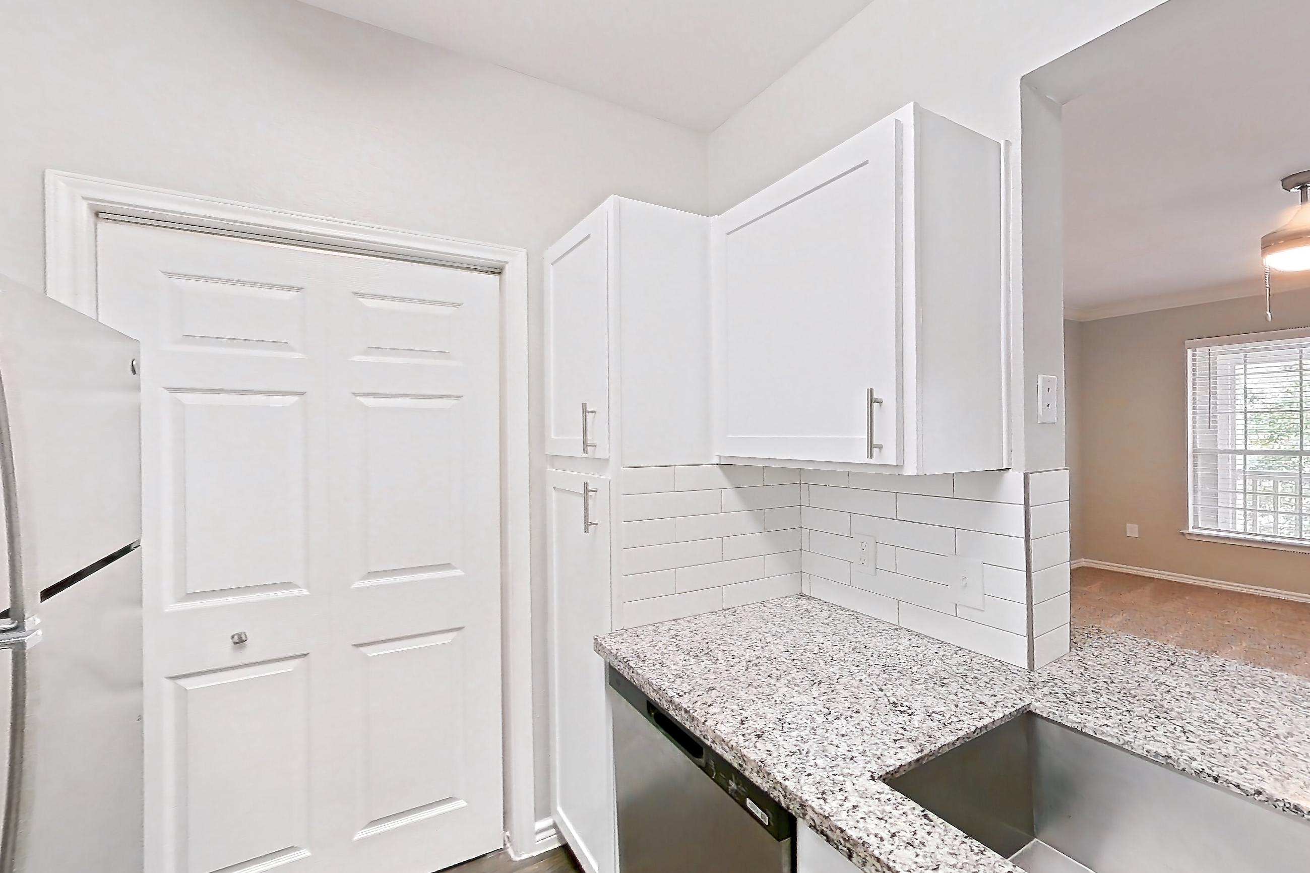 Kitchen with dark carpet, dark wood-finish flooring, dishwasher, electric range, light countertops, light stone countertops, oven/range, refrigerator, and stainless steel appliances, Apartment 0632 at Reserve at Kingwood