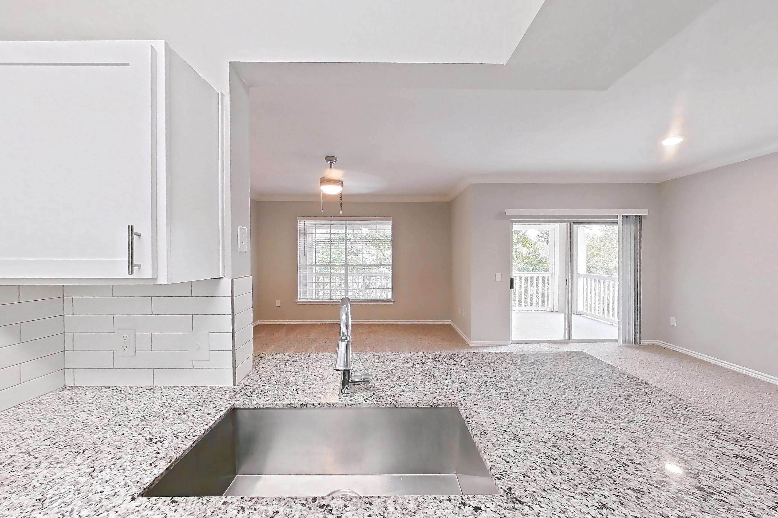 Kitchen with dark carpet, dark wood-finish flooring, dishwasher, electric range, light countertops, light stone countertops, oven/range, refrigerator, and stainless steel appliances, Apartment 0632 at Reserve at Kingwood