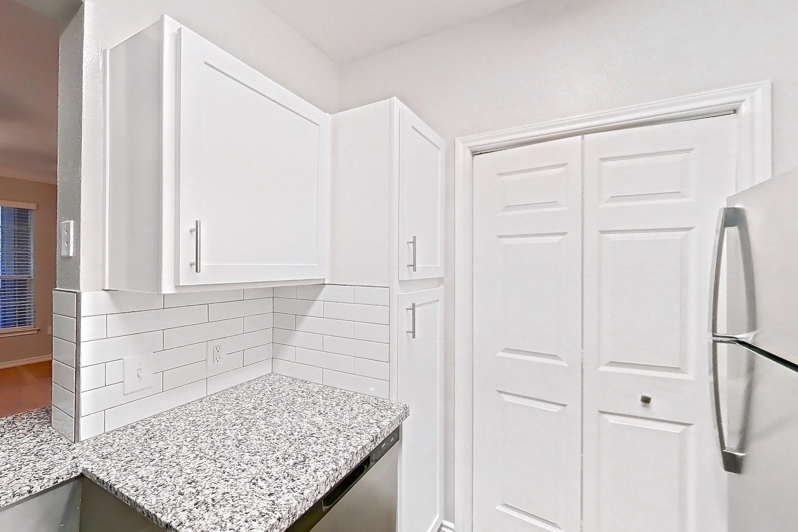 Kitchen with dishwasher, electric range, light countertops, light stone countertops, light wood-finish flooring, oven/range, refrigerator, and stainless steel appliances, Apartment 0727 at Reserve at Kingwood