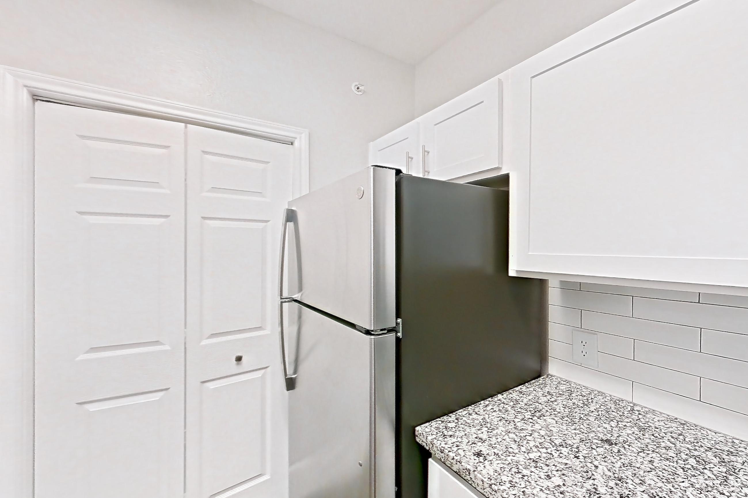 Kitchen with dishwasher, electric range, light countertops, light stone countertops, light wood-finish flooring, oven/range, refrigerator, and stainless steel appliances, Apartment 0727 at Reserve at Kingwood