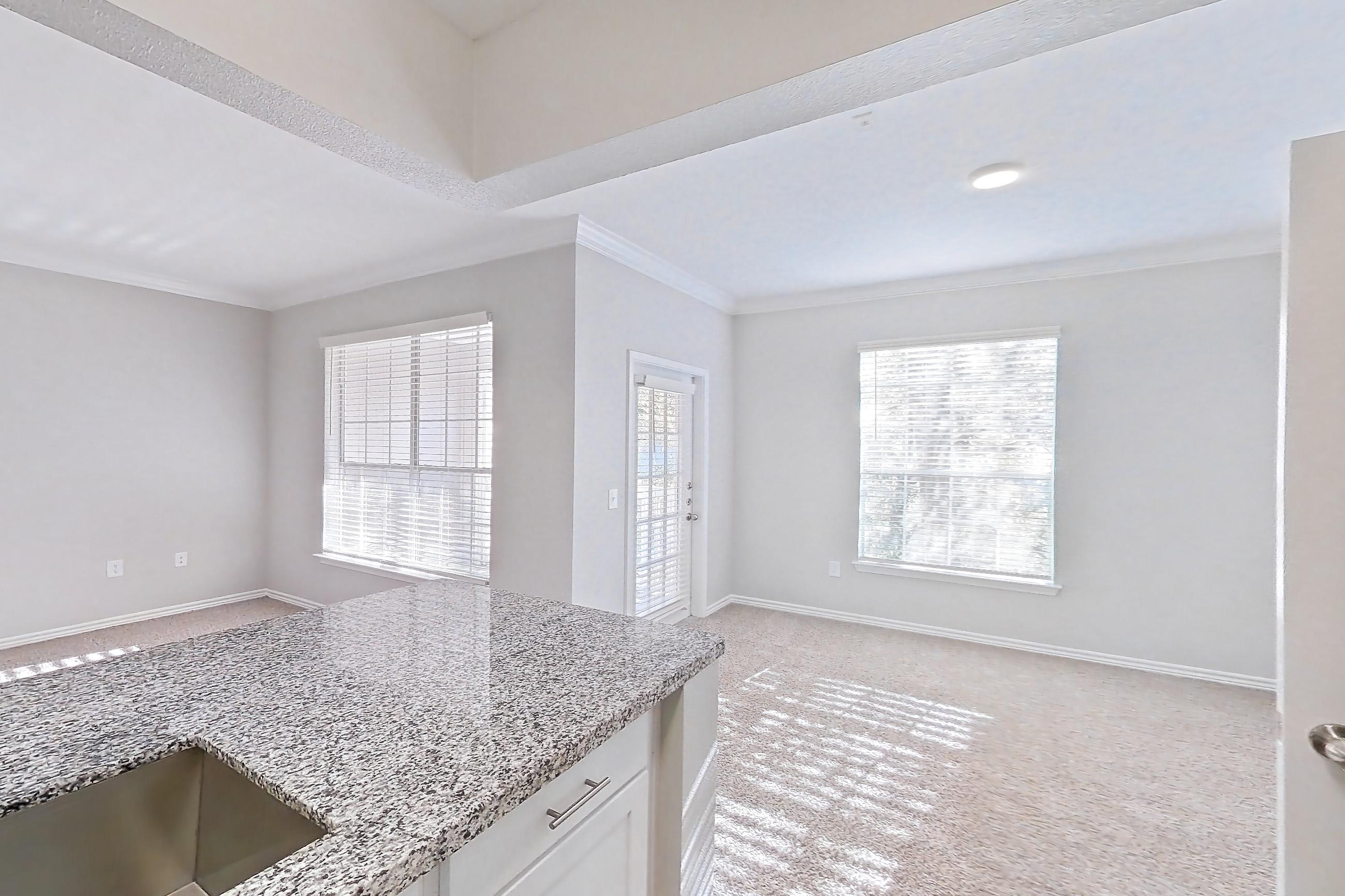Kitchen with dark wood-finish flooring, dishwasher, electric range, light carpet, light countertops, light stone countertops, light wood-finish flooring, oven/range, refrigerator, and stainless steel appliances, Apartment 0535 at Reserve at Kingwood