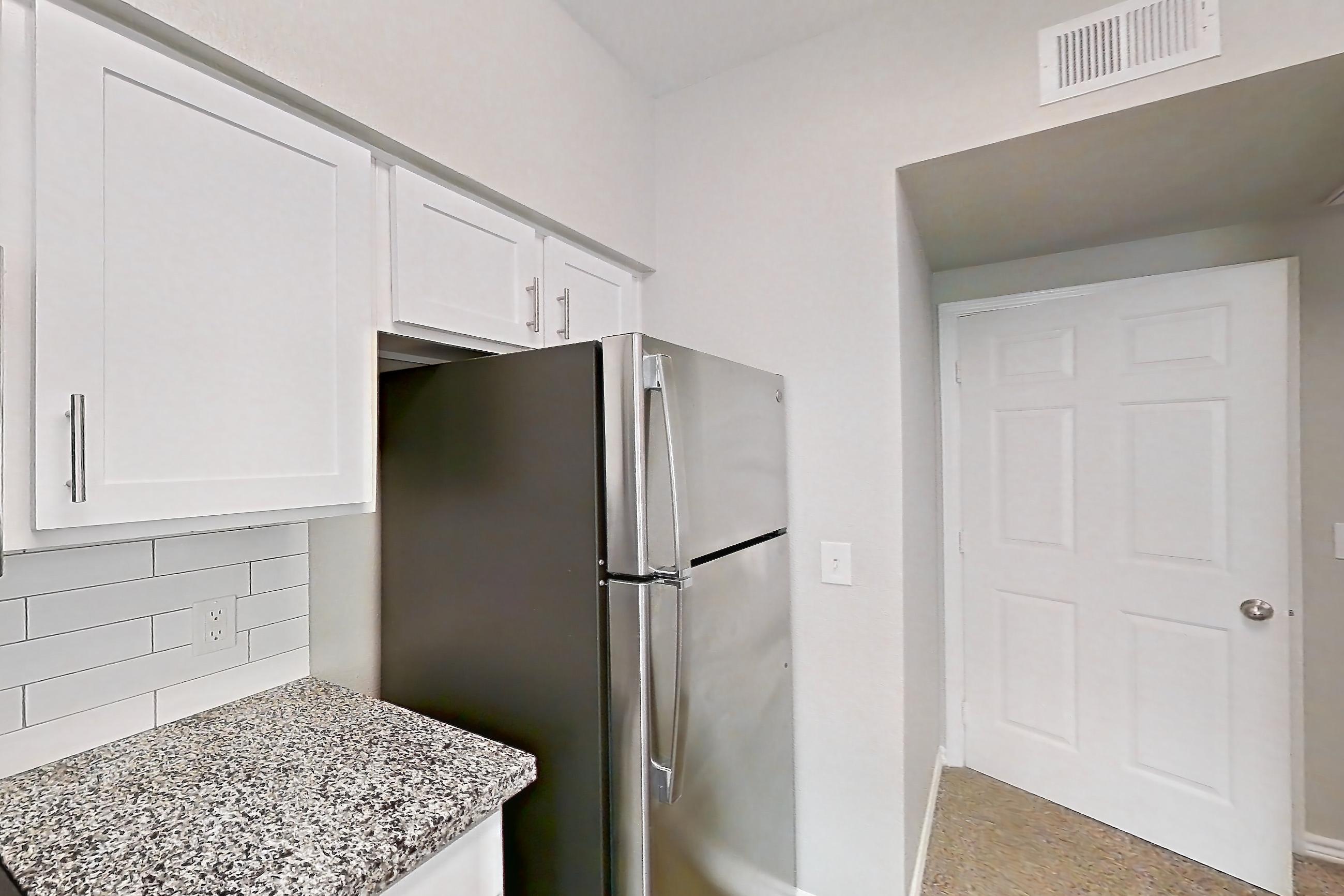 Kitchen with dark wood-finish flooring, dishwasher, electric range, light carpet, light countertops, light stone countertops, light wood-finish flooring, oven/range, refrigerator, and stainless steel appliances, Apartment 0535 at Reserve at Kingwood