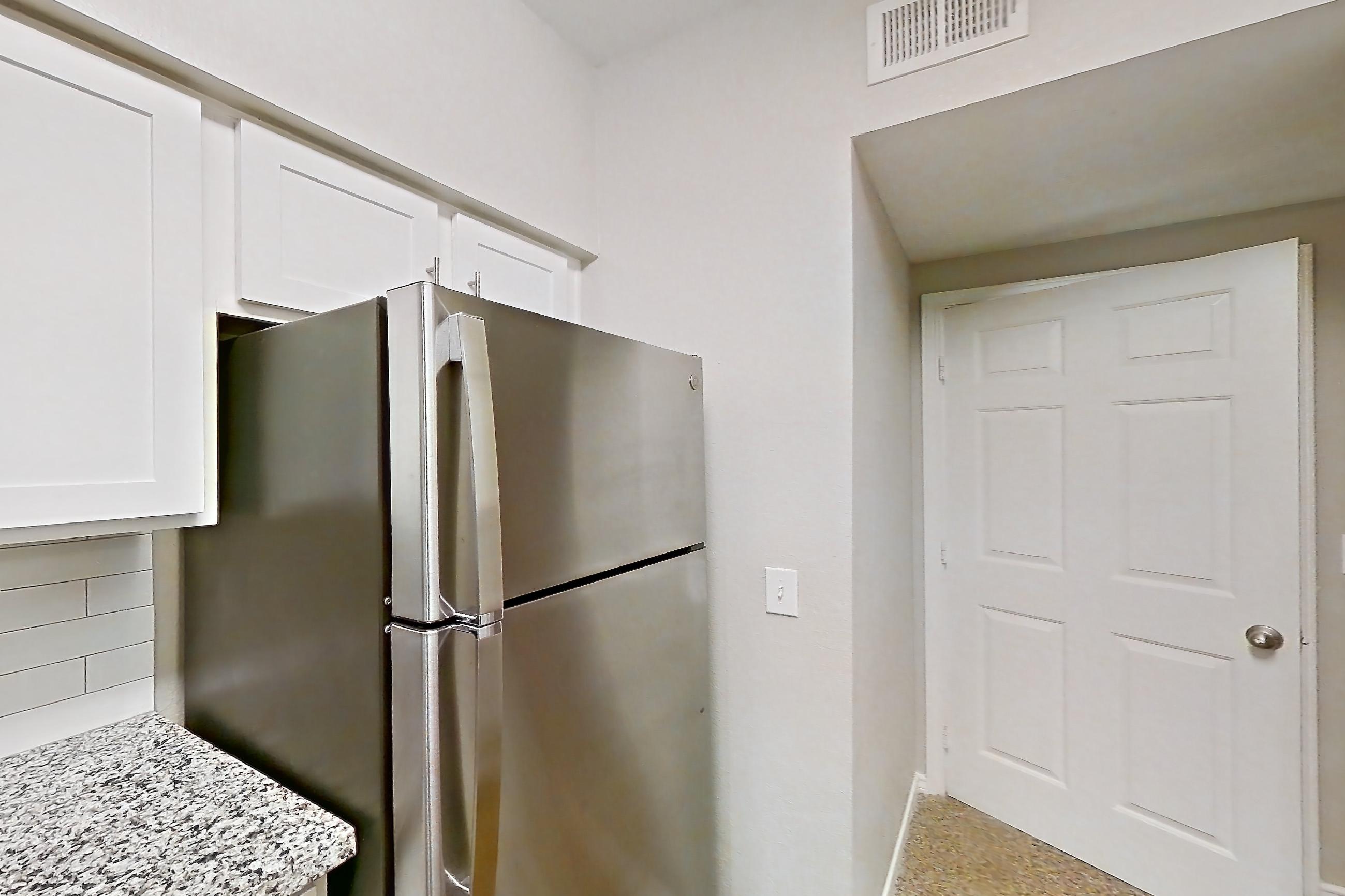 Kitchen with dark carpet, dark wood-finish flooring, dishwasher, electric range, light stone countertops, light wood-finish flooring, oven/range, refrigerator, and stainless steel appliances, Apartment 0920 at Reserve at Kingwood