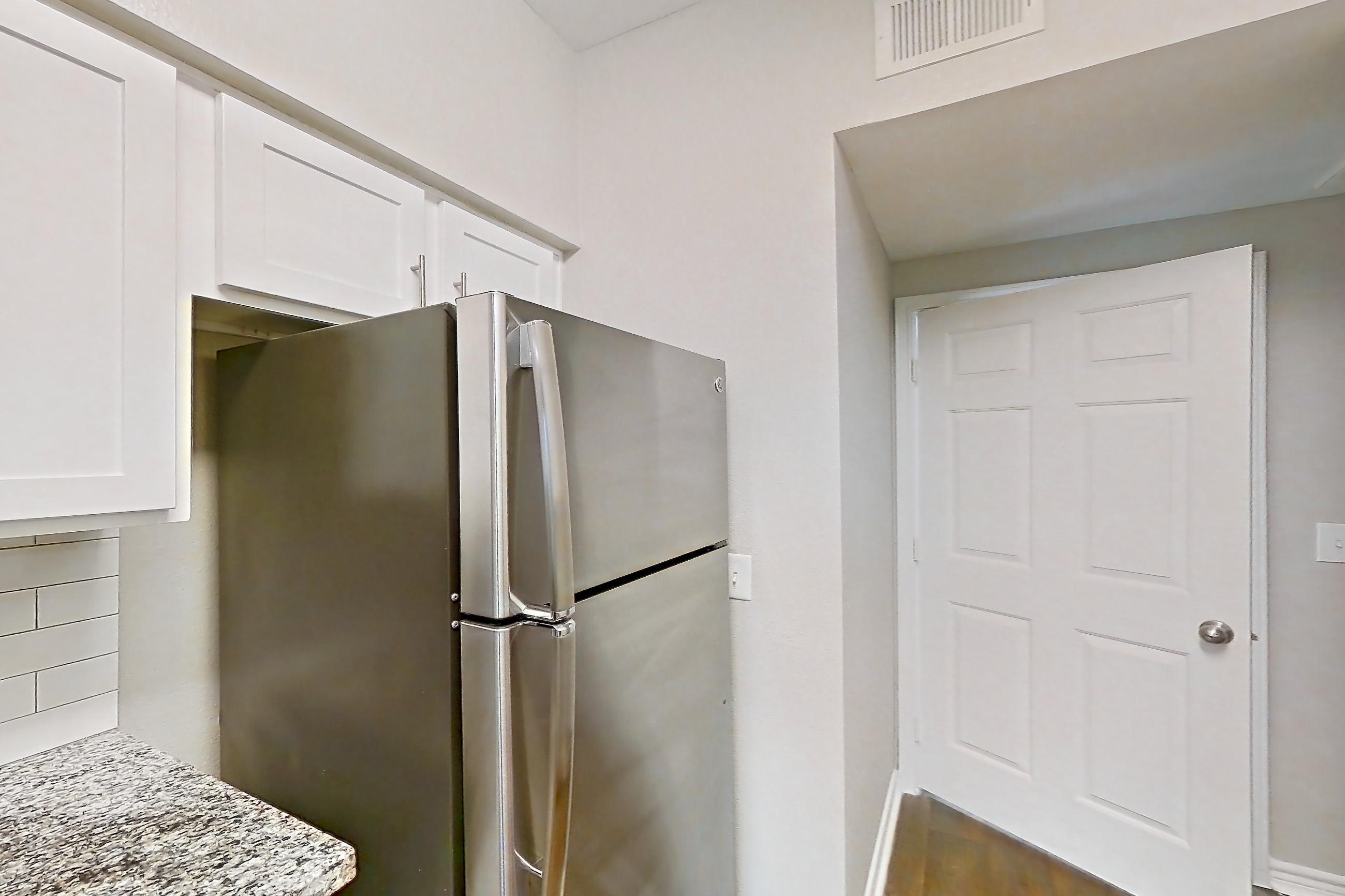 Kitchen with dark wood-finish flooring, dishwasher, electric range, glass shower door, light stone countertops, oven/range, refrigerator, stainless steel appliances, stall shower, and walk-in shower, Apartment 1115 at Reserve at Kingwood