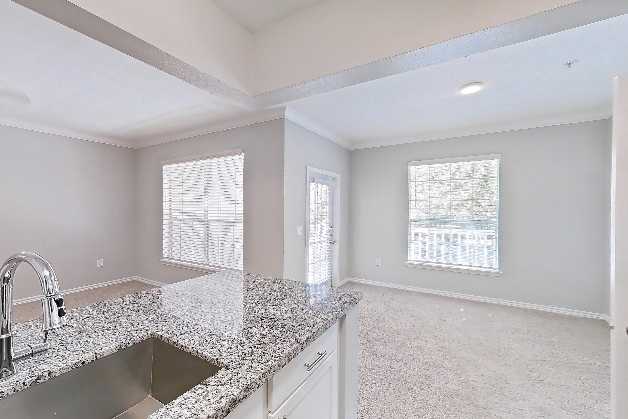 Kitchen with dark carpet, dark wood-finish flooring, dishwasher, electric range, light stone countertops, oven/range, refrigerator, and stainless steel appliances, Apartment 1121 at Reserve at Kingwood