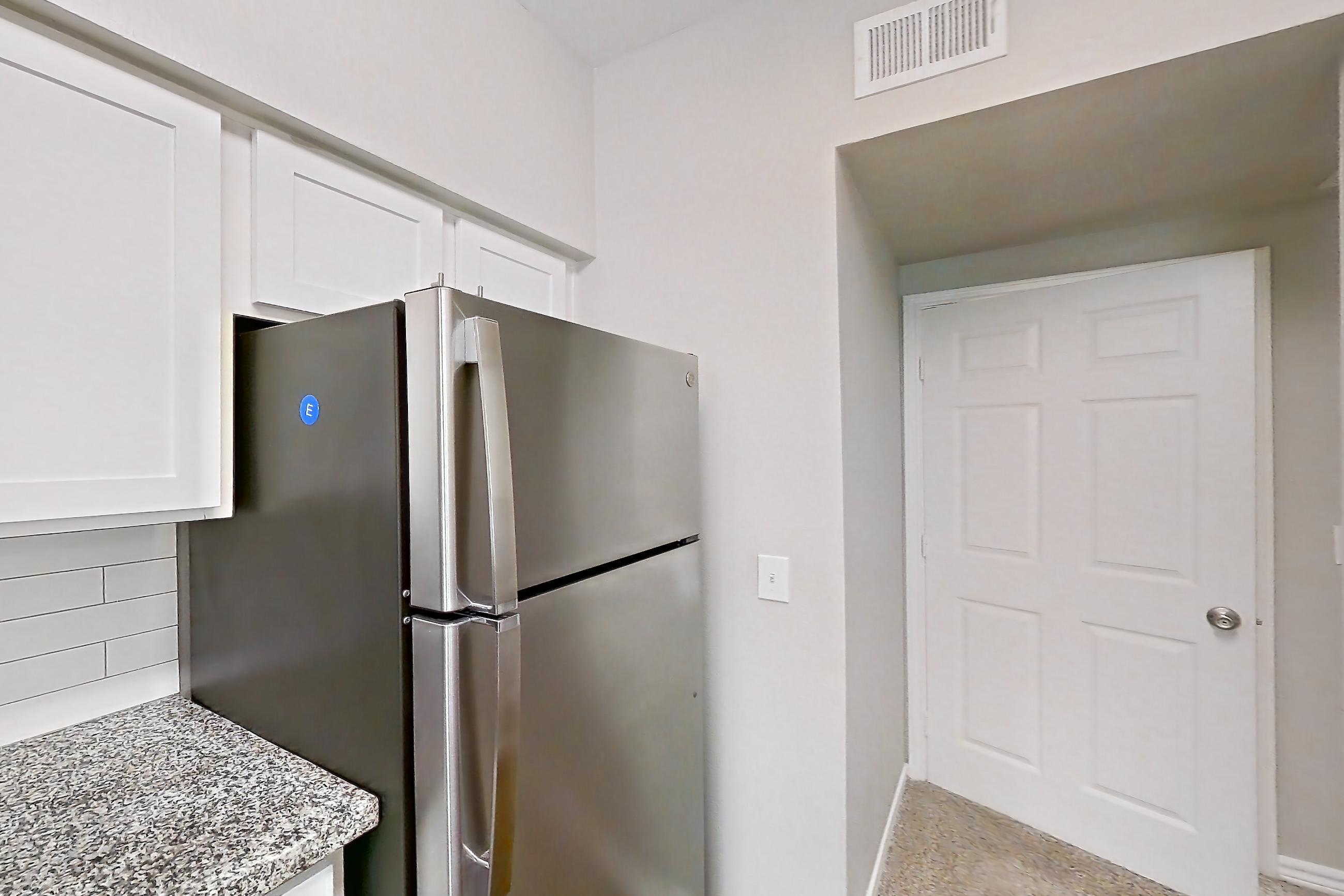 Kitchen with dark carpet, dark wood-finish flooring, dishwasher, electric range, light stone countertops, oven/range, refrigerator, and stainless steel appliances, Apartment 1121 at Reserve at Kingwood