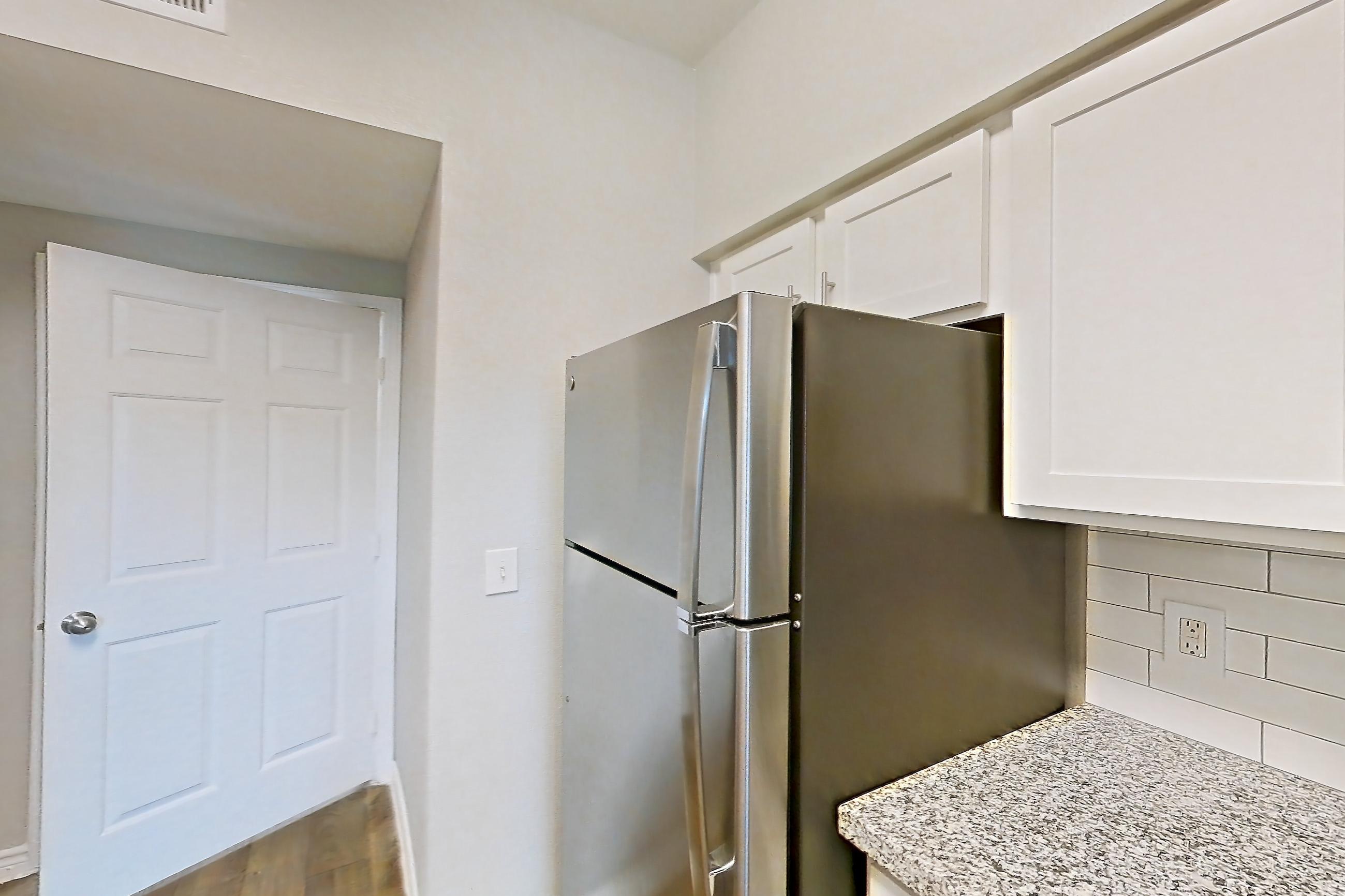 Kitchen with dark wood-finish flooring, dishwasher, electric range, light countertops, light stone countertops, light wood-finish flooring, oven/range, refrigerator, and stainless steel appliances, Apartment 0914 at Reserve at Kingwood