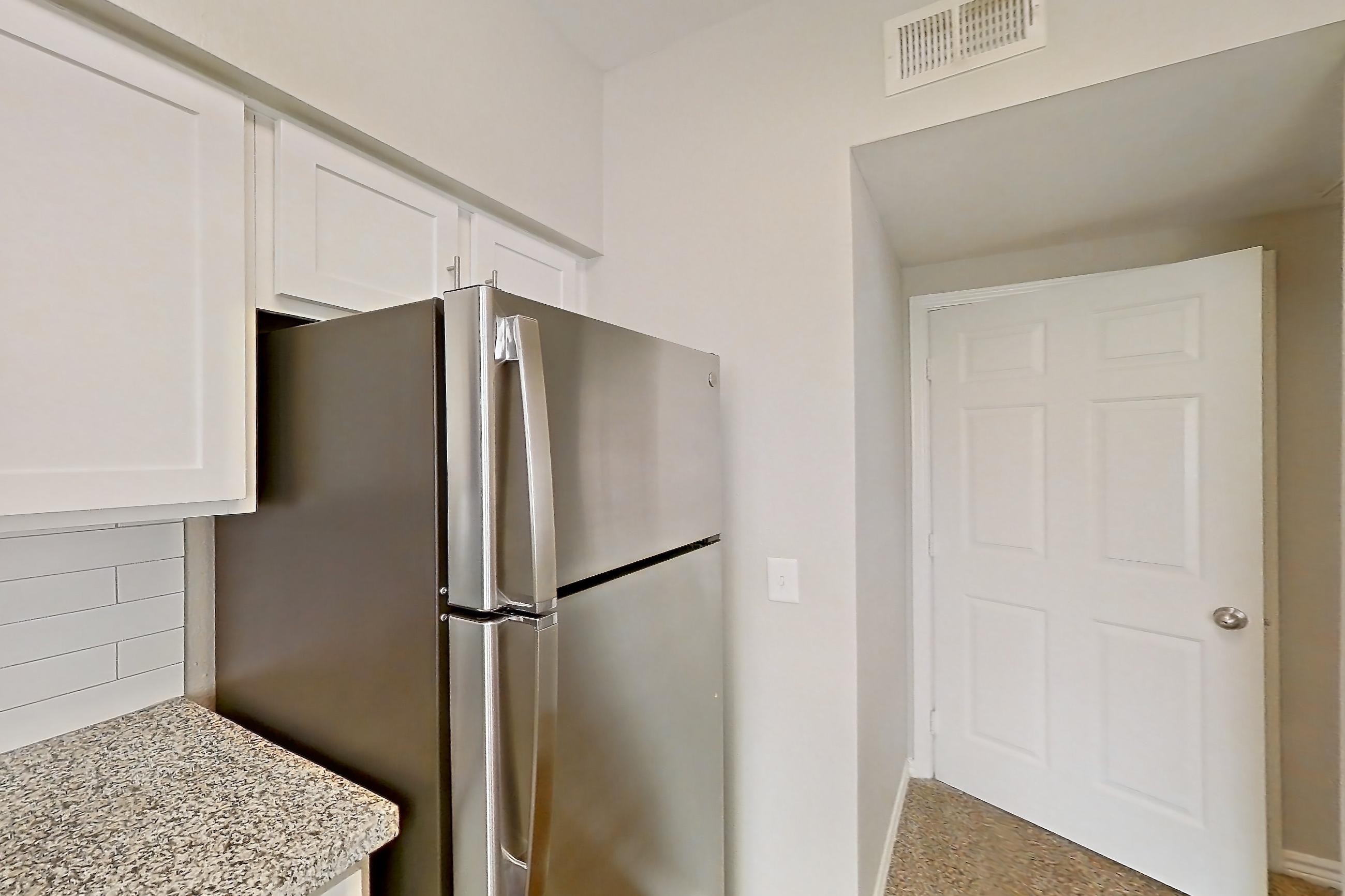 Kitchen with dark carpet, dark wood-finish flooring, dishwasher, electric range, light stone countertops, oven/range, refrigerator, and stainless steel appliances, Apartment 1230 at Reserve at Kingwood
