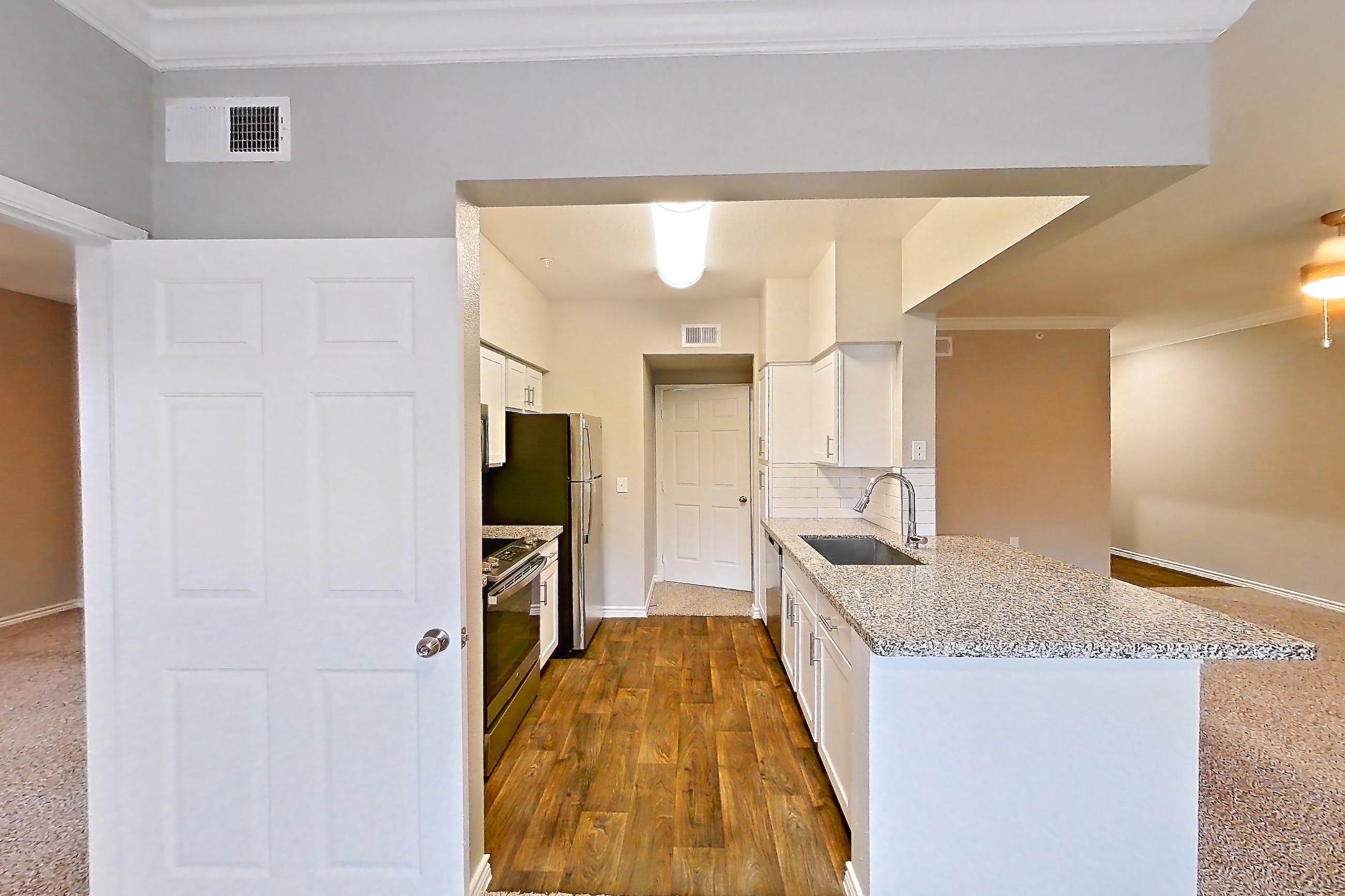 Dining room with dark carpet, dark wood-finish flooring, light stone countertops, oven/range, refrigerator, and stainless steel appliances, Apartment 0435 at Reserve at Kingwood