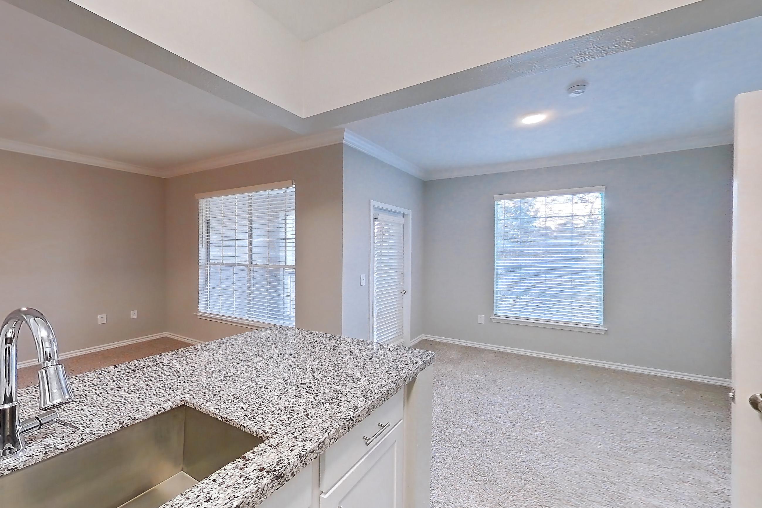 Kitchen with dark carpet, dark wood-finish flooring, dishwasher, electric range, light stone countertops, oven/range, refrigerator, and stainless steel appliances, Apartment 0435 at Reserve at Kingwood