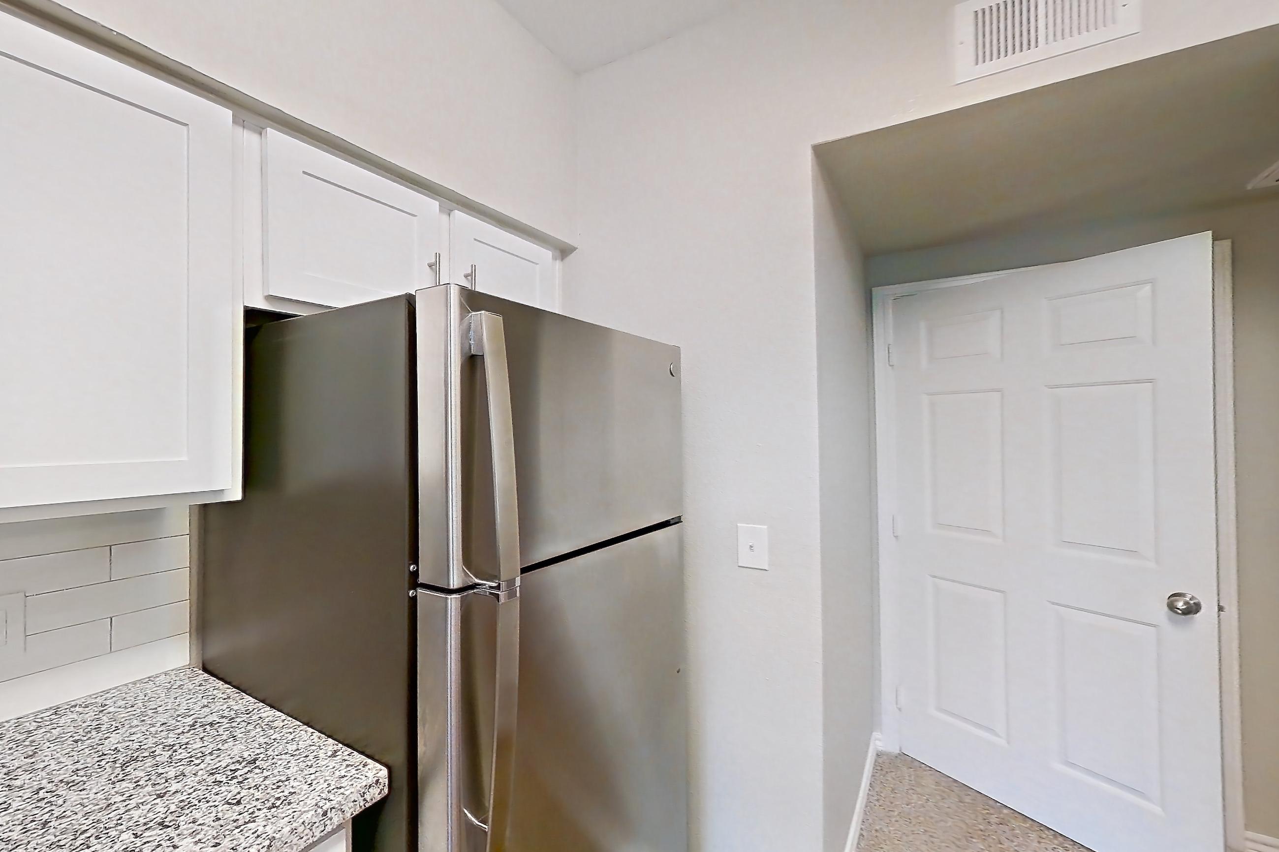 Kitchen with dark carpet, dark wood-finish flooring, dishwasher, electric range, light stone countertops, oven/range, refrigerator, and stainless steel appliances, Apartment 0435 at Reserve at Kingwood