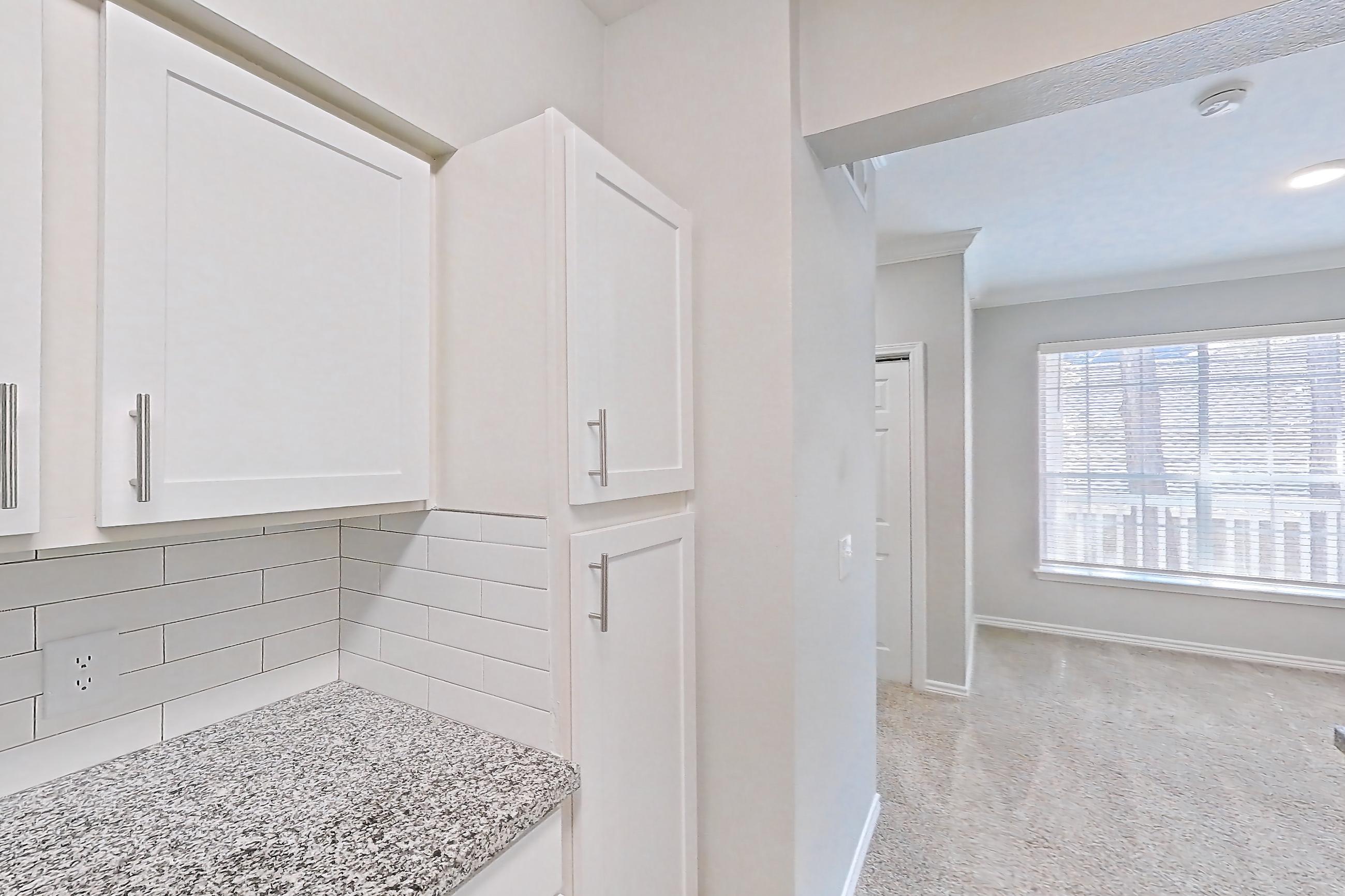 Kitchen with dark carpet, dark wood-finish flooring, dishwasher, electric range, light countertops, light stone countertops, microwave, oven/range, refrigerator, stainless steel appliances, and white appliances, Apartment 0529 at Reserve at Kingwood