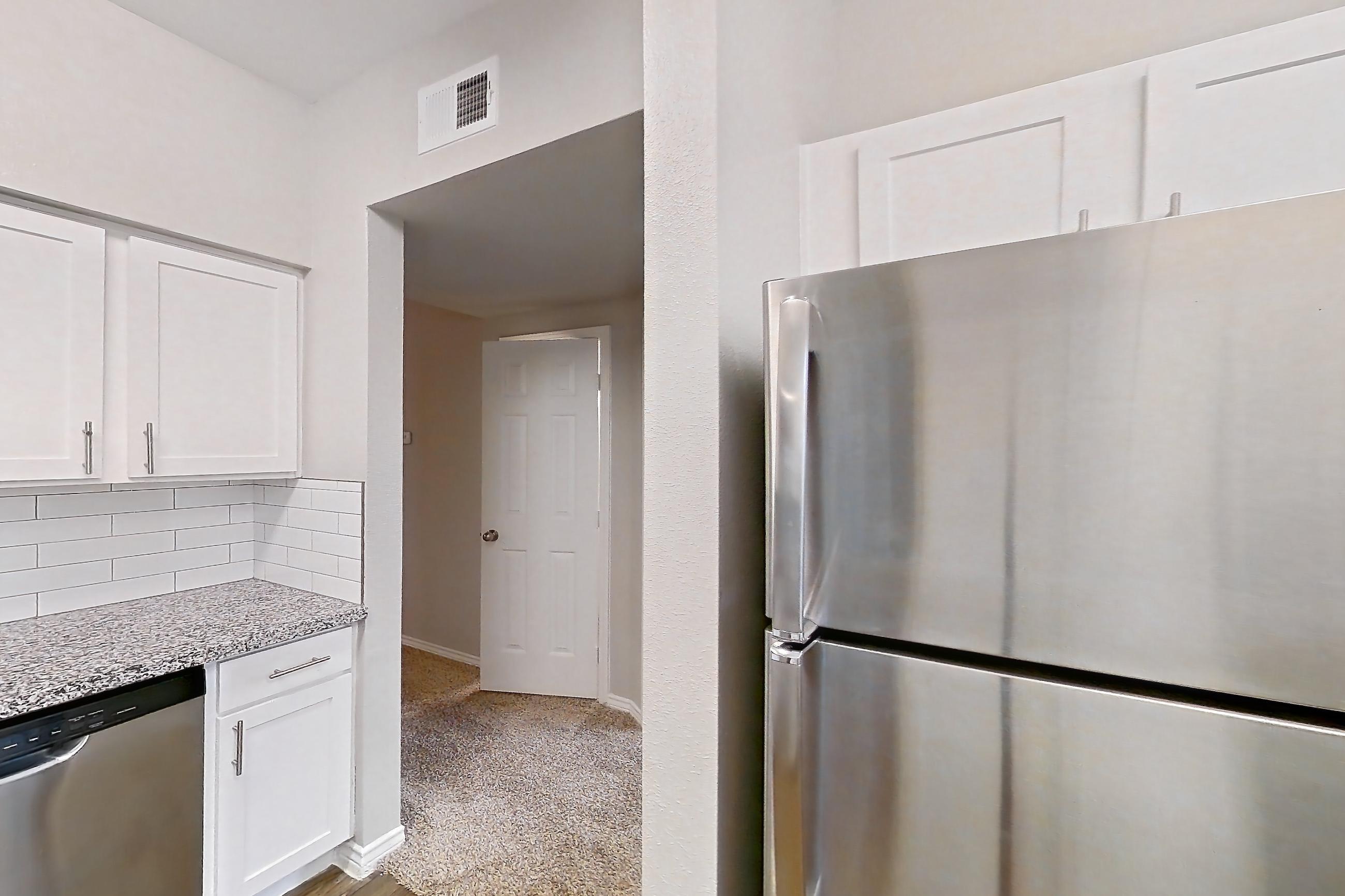 Kitchen with dishwasher, electric range, light carpet, light countertops, light stone countertops, light wood-finish flooring, microwave, oven/range, refrigerator, and stainless steel appliances, Apartment 1031 at Reserve at Kingwood