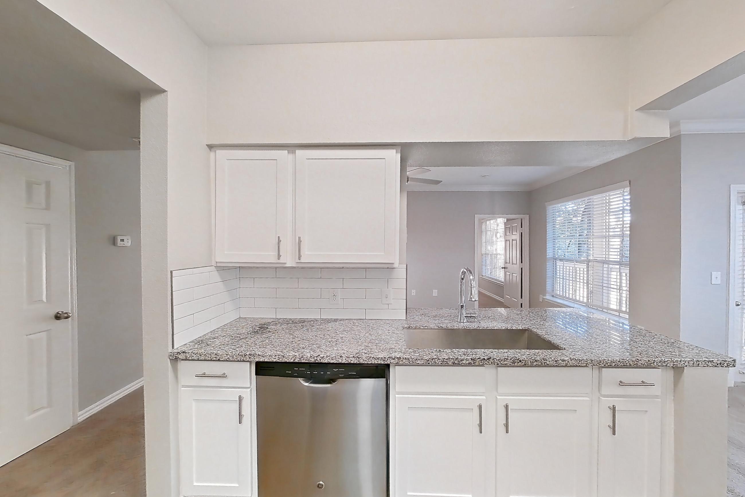 Kitchen with dark carpet, dark wood-finish flooring, dishwasher, electric range, light stone countertops, oven/range, refrigerator, and stainless steel appliances, Apartment 0828 at Reserve at Kingwood