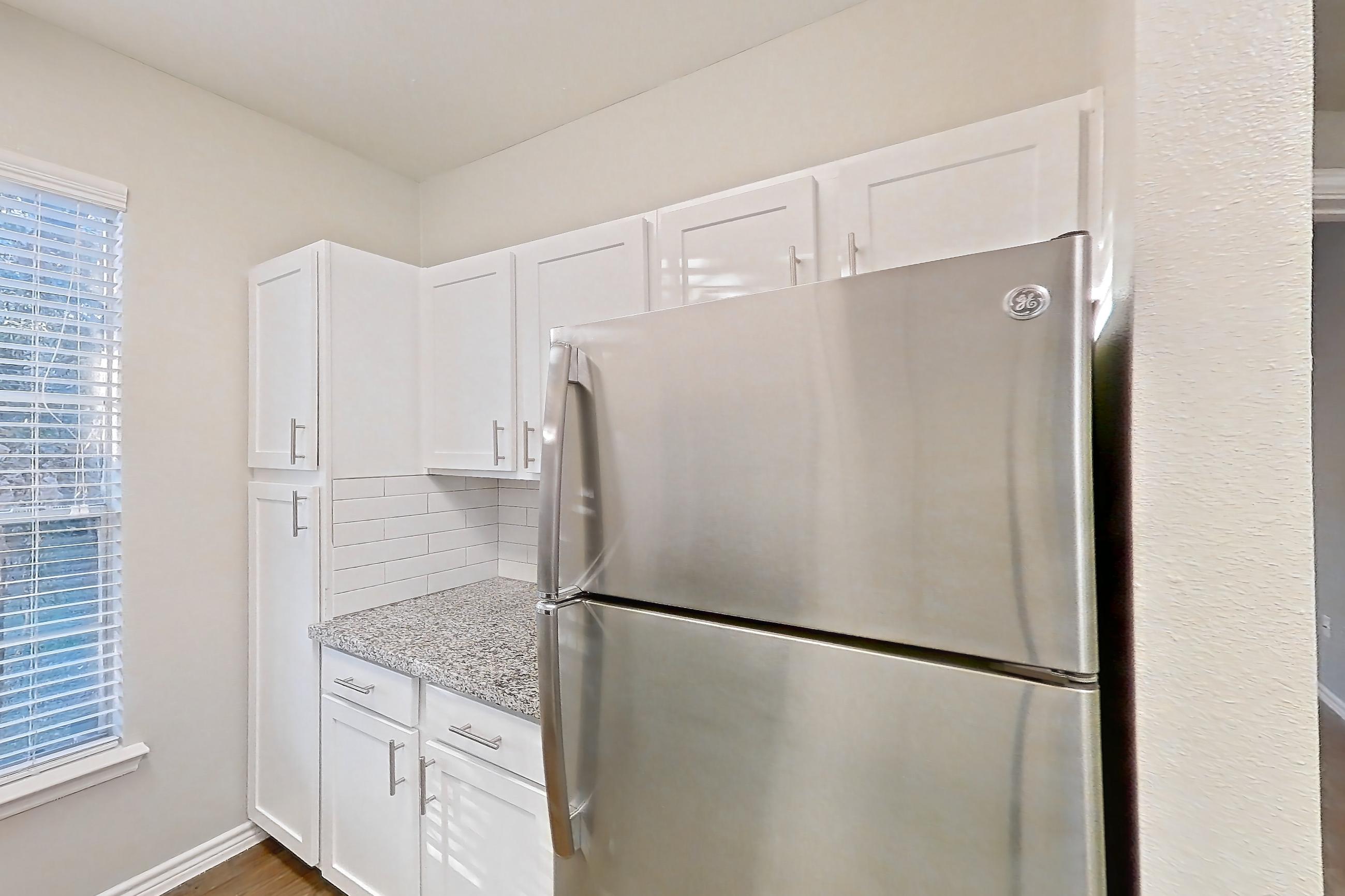 Kitchen with dark carpet, dark wood-finish flooring, dishwasher, electric range, light stone countertops, oven/range, refrigerator, and stainless steel appliances, Apartment 0828 at Reserve at Kingwood