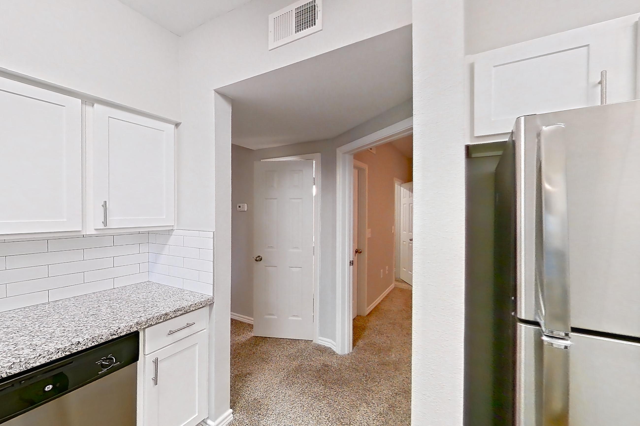 Kitchen with dark carpet, dark wood-finish flooring, dishwasher, electric range, light carpet, light stone countertops, light wood-finish flooring, oven/range, refrigerator, and stainless steel appliances, Apartment 0825 at Reserve at Kingwood