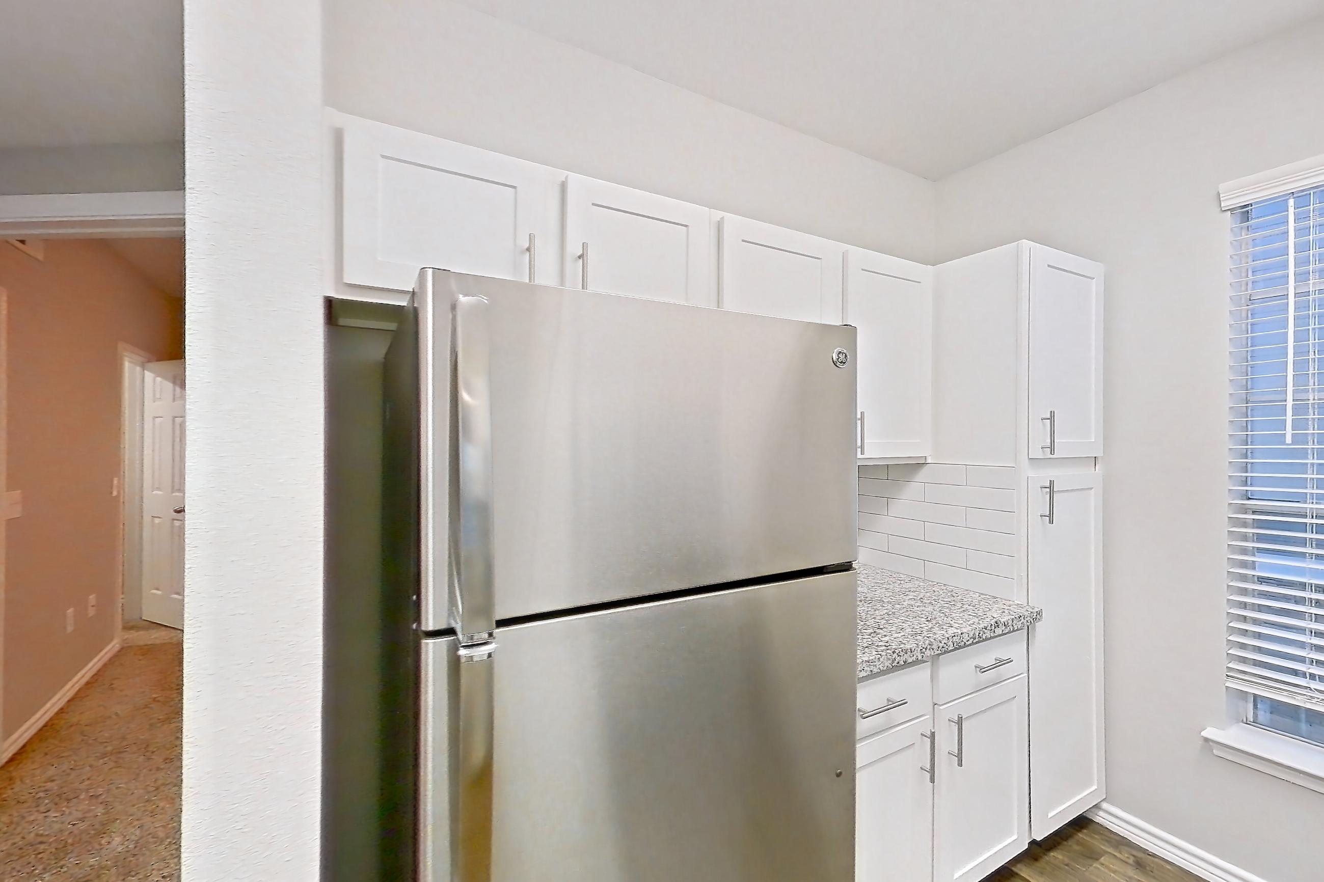 Kitchen with dark carpet, dark wood-finish flooring, dishwasher, electric range, light carpet, light stone countertops, light wood-finish flooring, oven/range, refrigerator, and stainless steel appliances, Apartment 0825 at Reserve at Kingwood