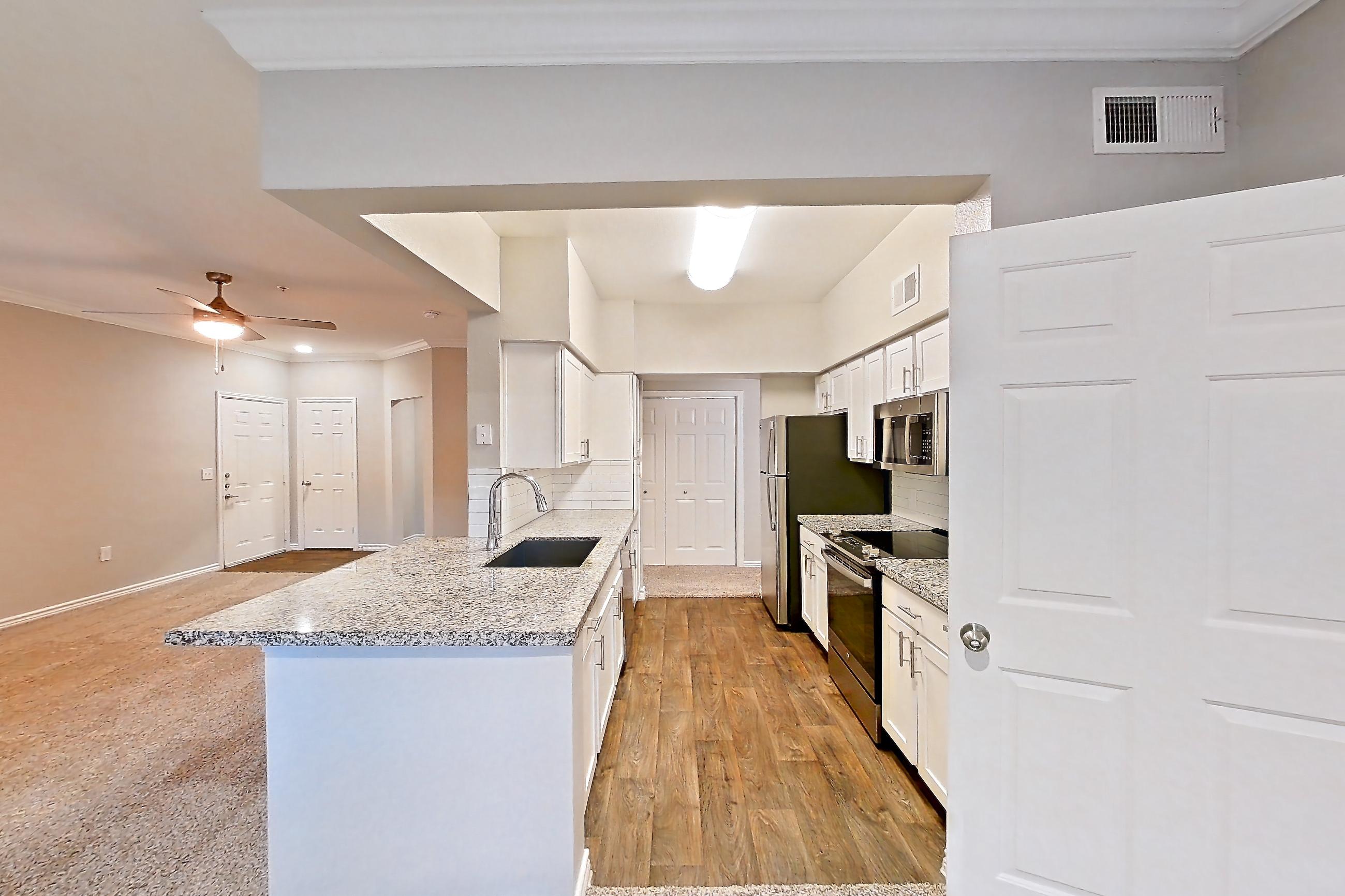 Dining room with electric range, light carpet, light stone countertops, light wood-finish flooring, oven/range, refrigerator, and stainless steel appliances, Apartment 1122 at Reserve at Kingwood