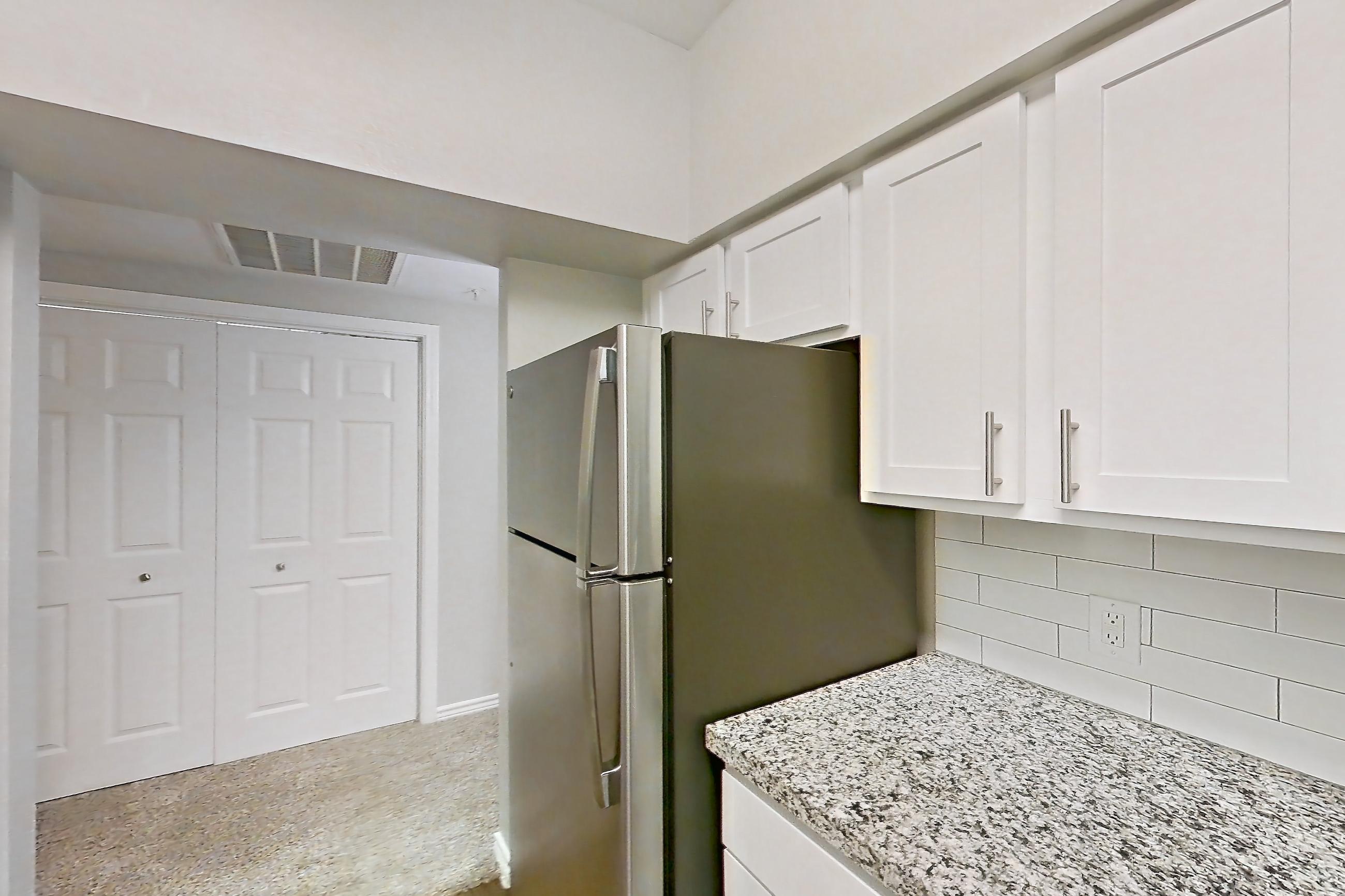 Kitchen with dark carpet, dark wood-finish flooring, dishwasher, electric range, light countertops, light stone countertops, oven/range, refrigerator, and stainless steel appliances, Apartment 1122 at Reserve at Kingwood