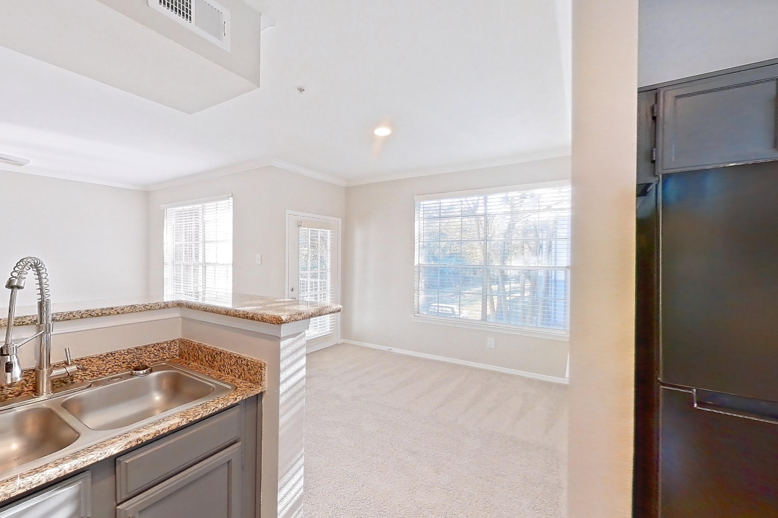 Kitchen with dark countertops, dishwasher, electric range, light carpet, light countertops, light stone countertops, light wood-finish flooring, microwave, oven/range, refrigerator, and stainless steel appliances, Apartment 0327 at Marquis Champions Forest
