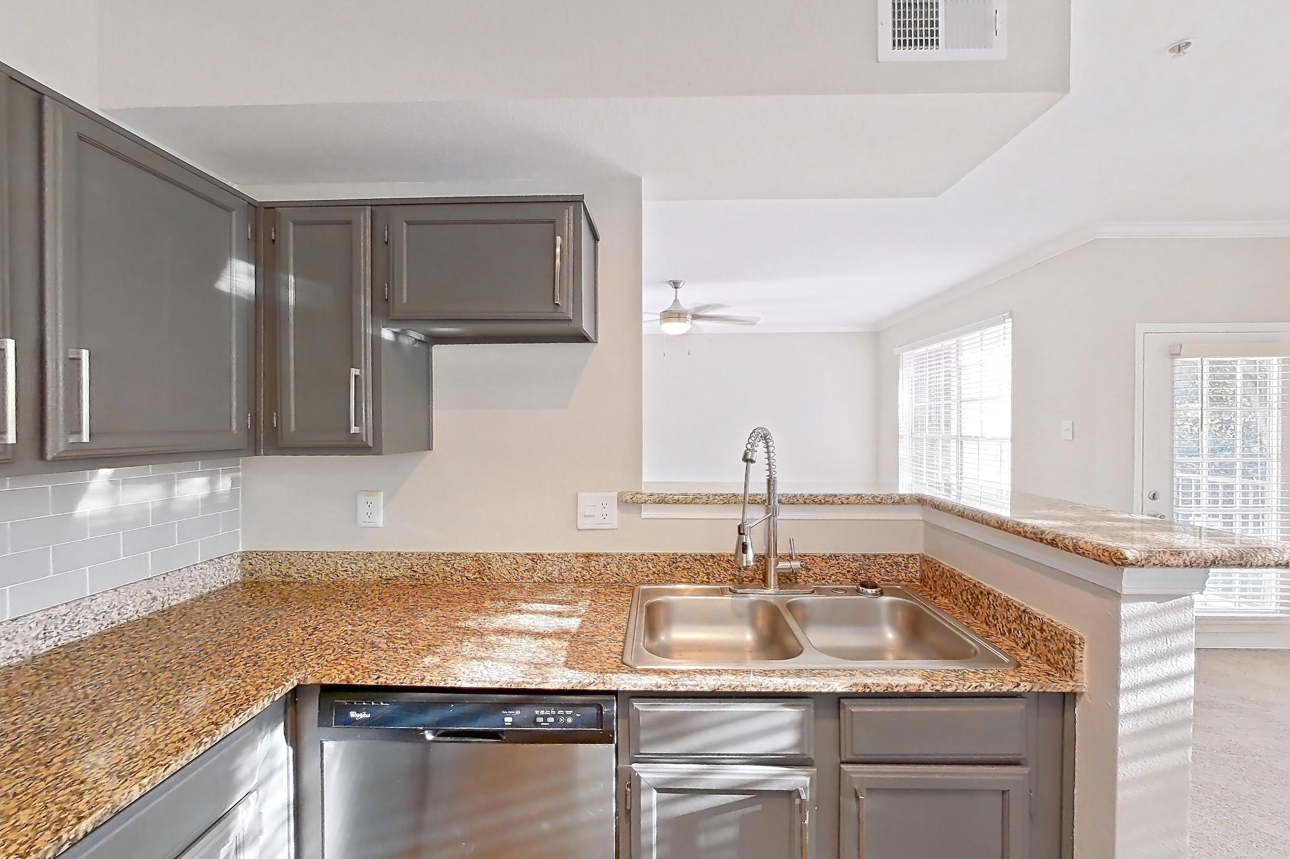 Kitchen with dark countertops, dishwasher, electric range, light carpet, light countertops, light stone countertops, light wood-finish flooring, microwave, oven/range, refrigerator, and stainless steel appliances, Apartment 0327 at Marquis Champions Forest