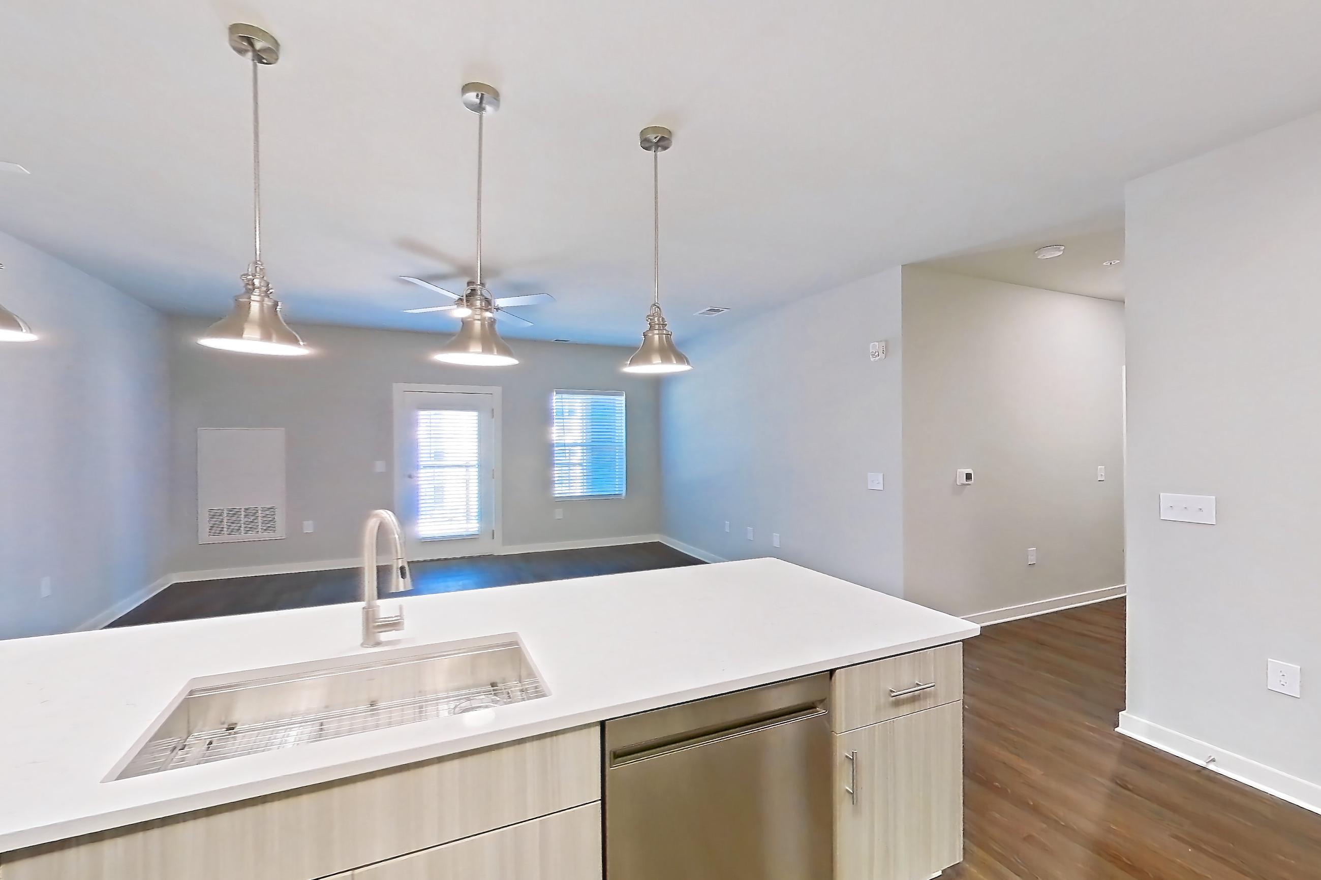 Kitchen with dark wood-finish flooring, dishwasher, electric range, light countertops, light stone countertops, light wood-finish flooring, microwave, oven/range, range hood, refrigerator, and stainless steel appliances, Apartment 3-305 at The Soho