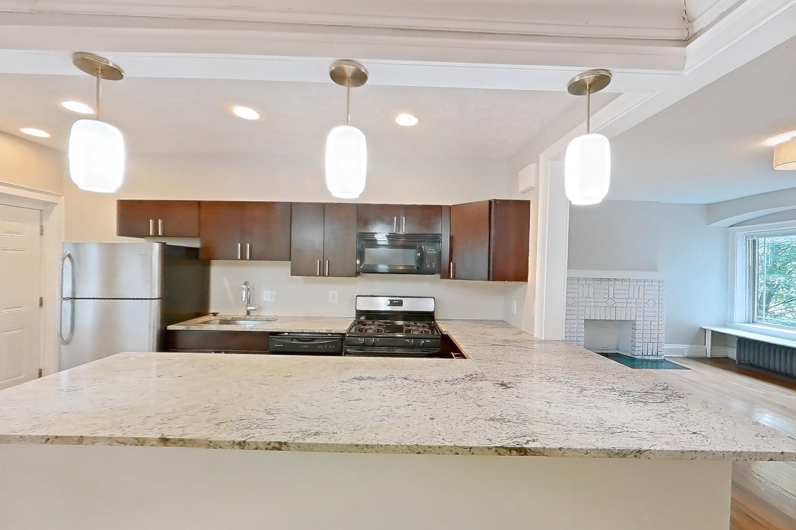 Dining room with black appliances, dishwasher, gas range, light countertops, light stone countertops, light wood-finish flooring, oven/range, radiator heat, refrigerator, stainless steel appliances, and wood-finish flooring, Apartment 48-04 at Integrity Cleveland Heights