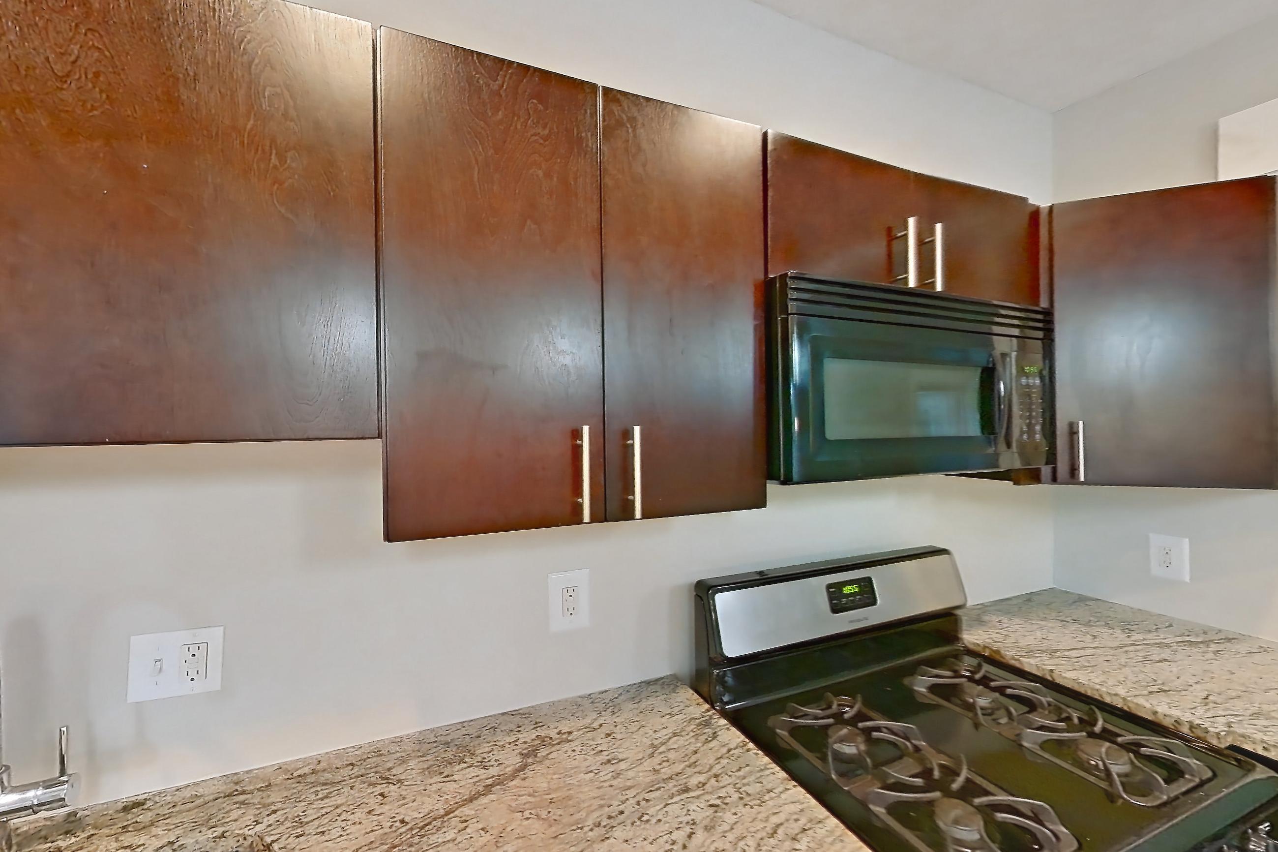 Kitchen with black appliances, dishwasher, gas range, light stone countertops, light tile flooring, microwave, oven/range, and stainless steel appliances, Apartment 48-04 at Integrity Cleveland Heights