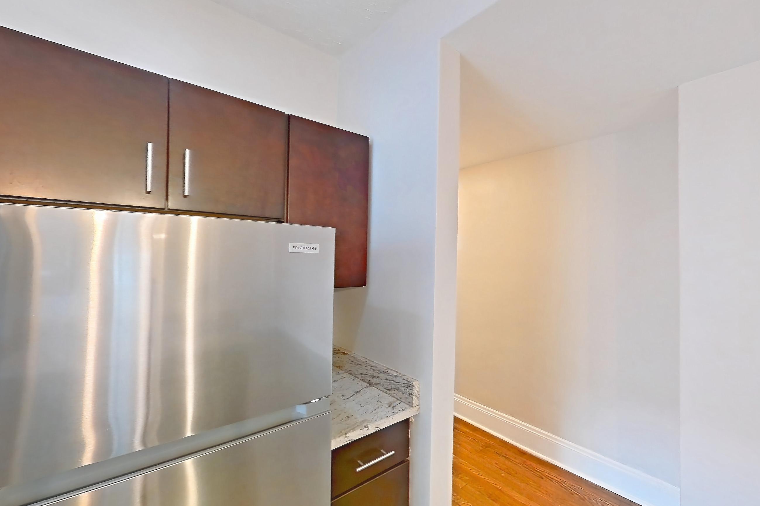 Kitchen with dark wood-finish flooring, dishwasher, gas range, light countertops, light stone countertops, light wood-finish flooring, microwave, oven/range, refrigerator, and stainless steel appliances, Apartment 5 at Integrity Cleveland Heights 
