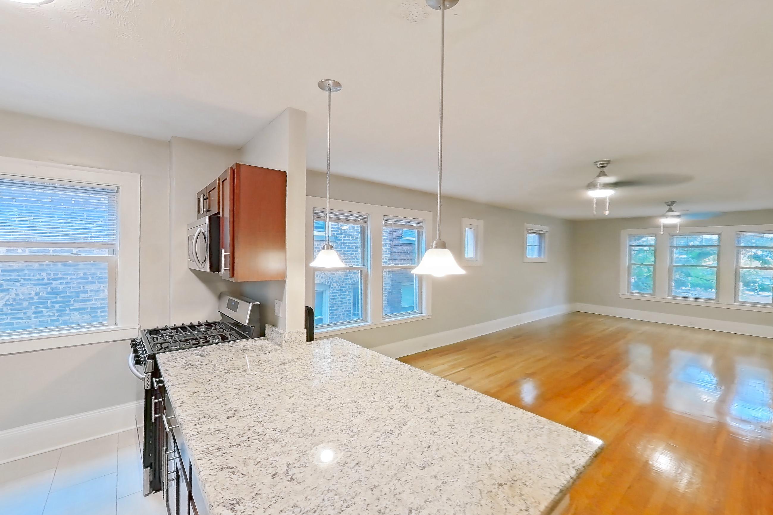 Kitchen with dishwasher, gas range, in-unit laundry, light countertops, light stone countertops, light wood-finish flooring, oven/range, refrigerator, and stainless steel appliances, Apartment 302 at Integrity Cleveland Heights