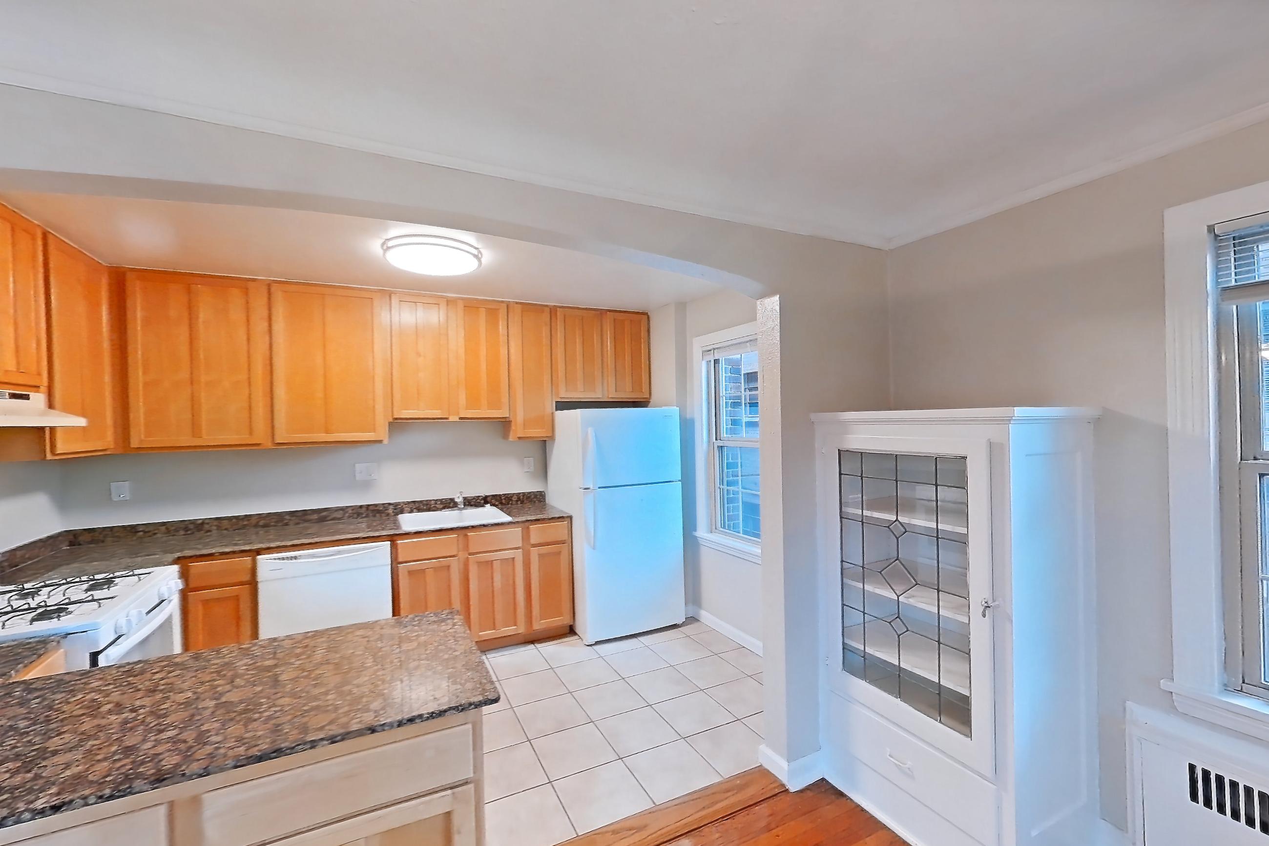 Dining room with dark stone countertops, dishwasher, gas range, light wood-finish flooring, oven/range, refrigerator, white appliances, and wood-finish flooring, Apartment 201 at Integrity Cleveland Heights