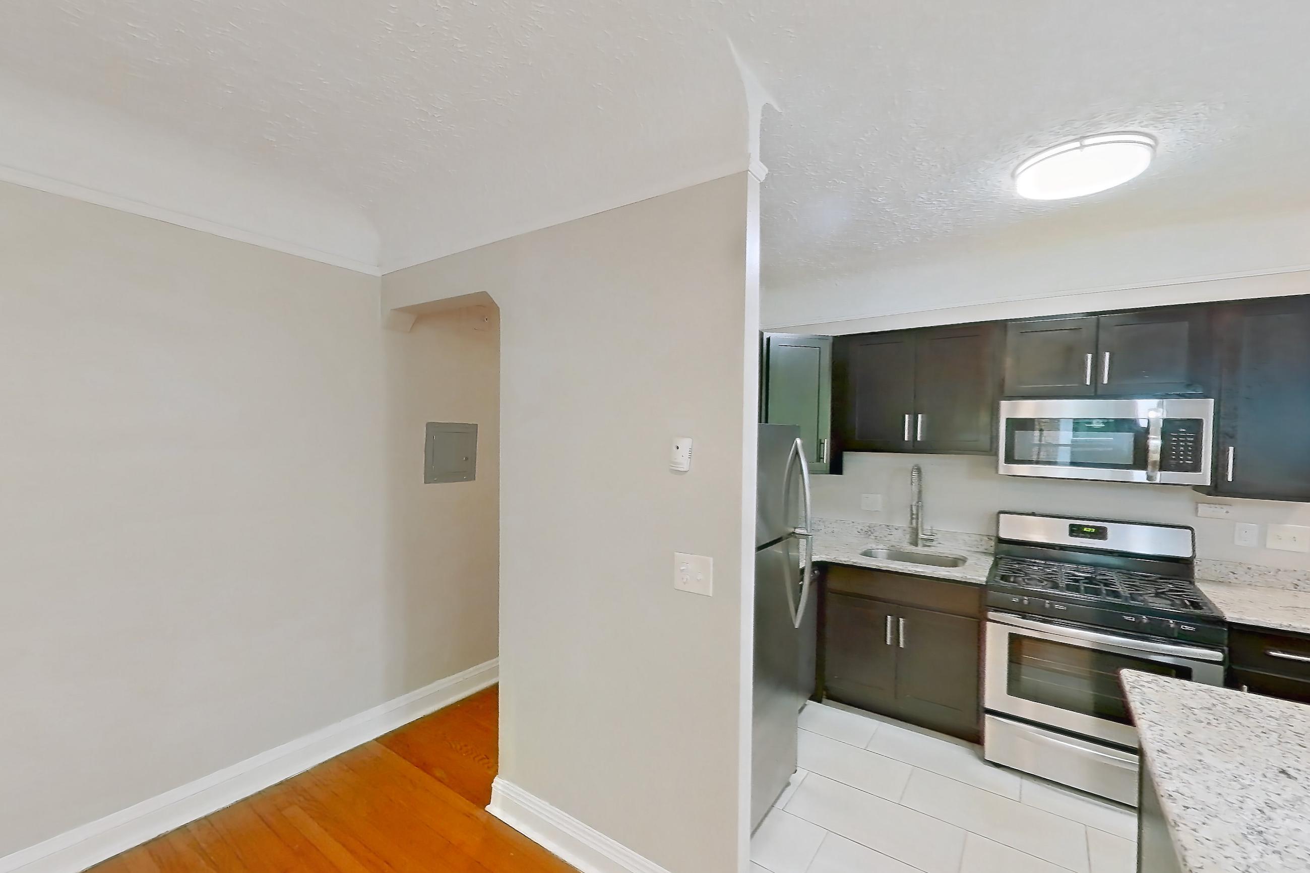 Dining room with gas range, light countertops, light stone countertops, light wood-finish flooring, oven/range, radiator heat, stainless steel appliances, and wood-finish flooring, Apartment 302 at Integrity Gold Coast