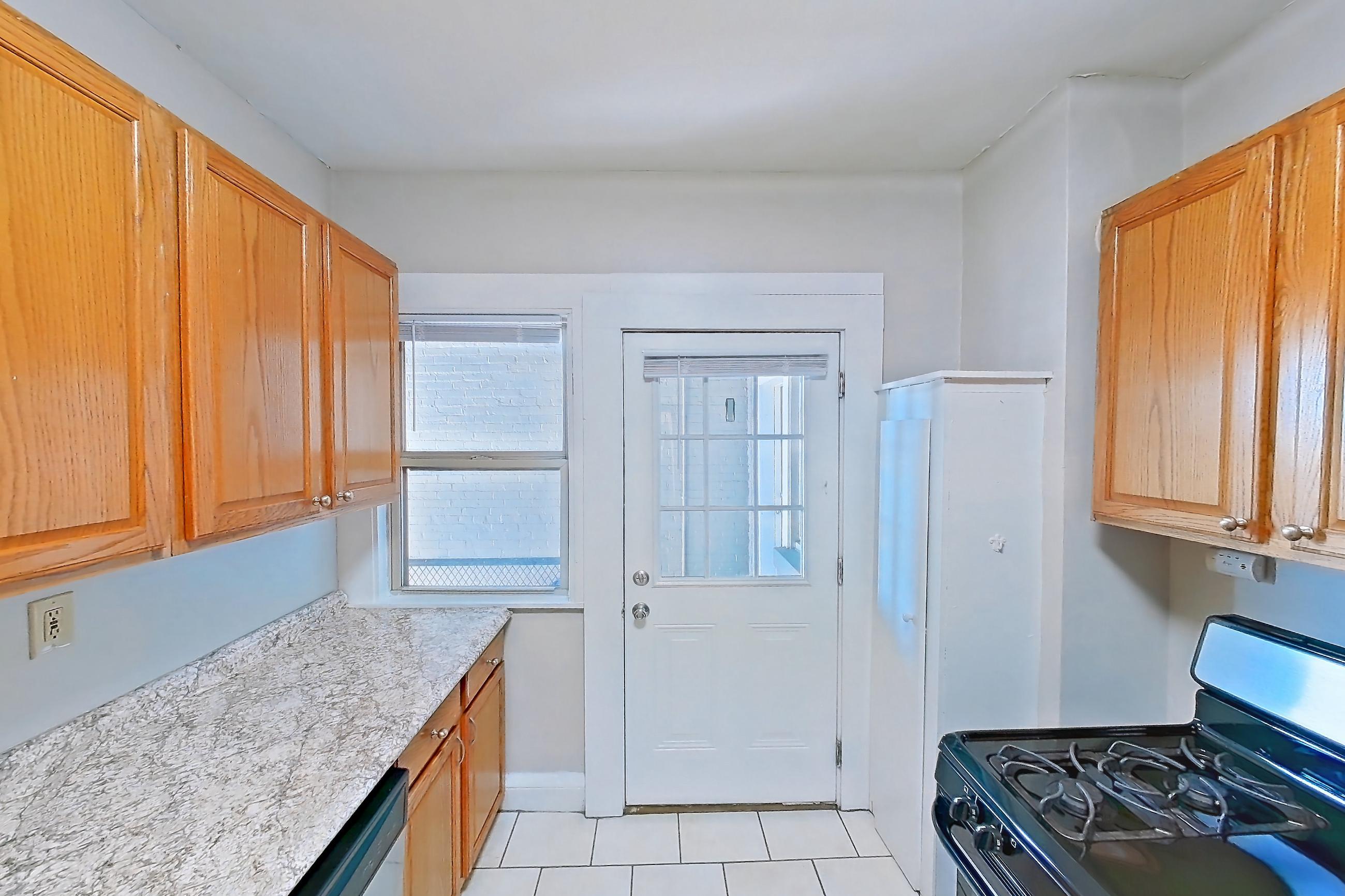 Kitchen with dishwasher, gas range, light countertops, light stone countertops, light tile flooring, oven/range, refrigerator, and stainless steel appliances, Apartment 97-17 at Integrity Gold Coast