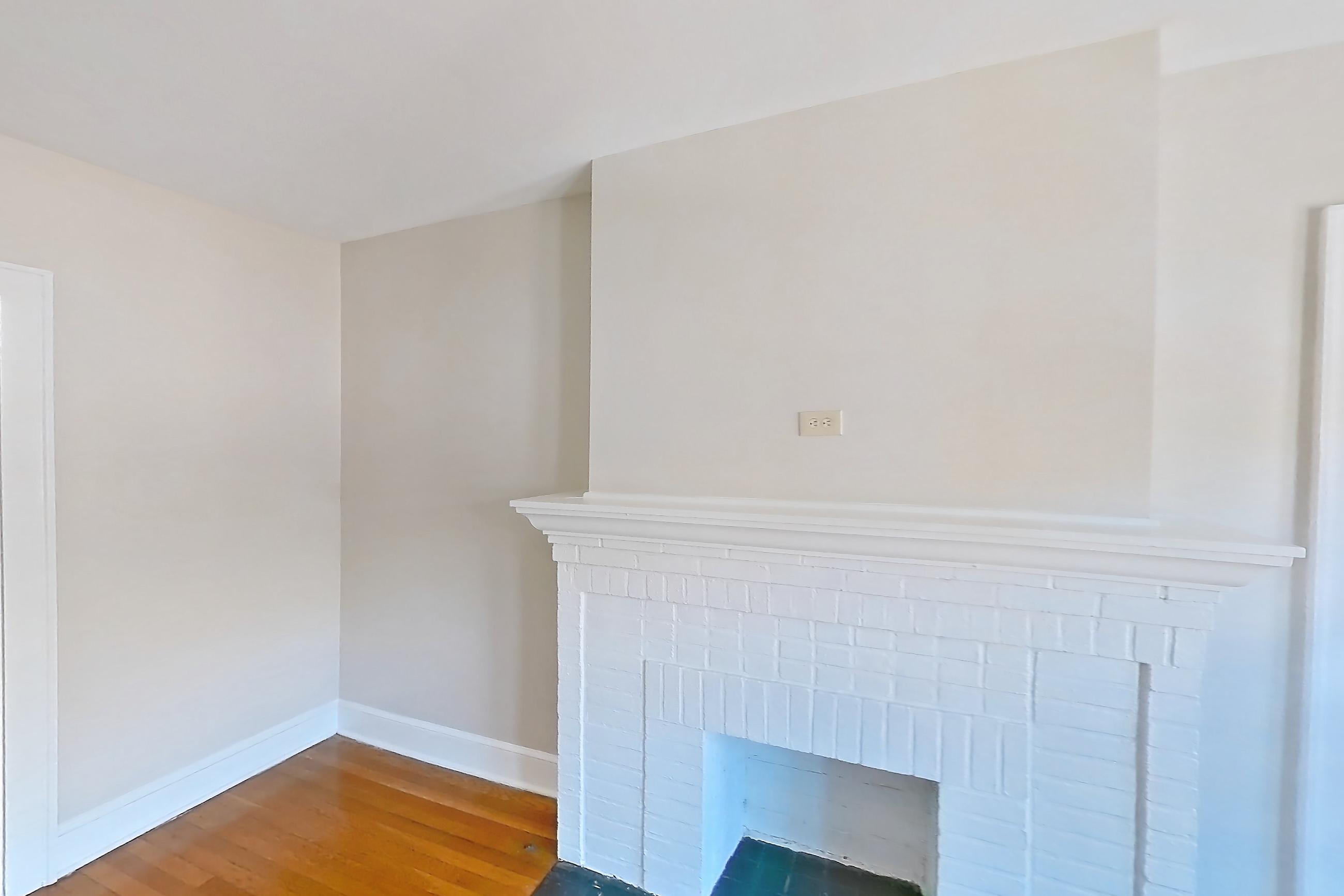 Living room with brick fireplace, fireplace, light wood-finish flooring, and wood-finish flooring, Apartment 97-17 at Integrity Gold Coast
