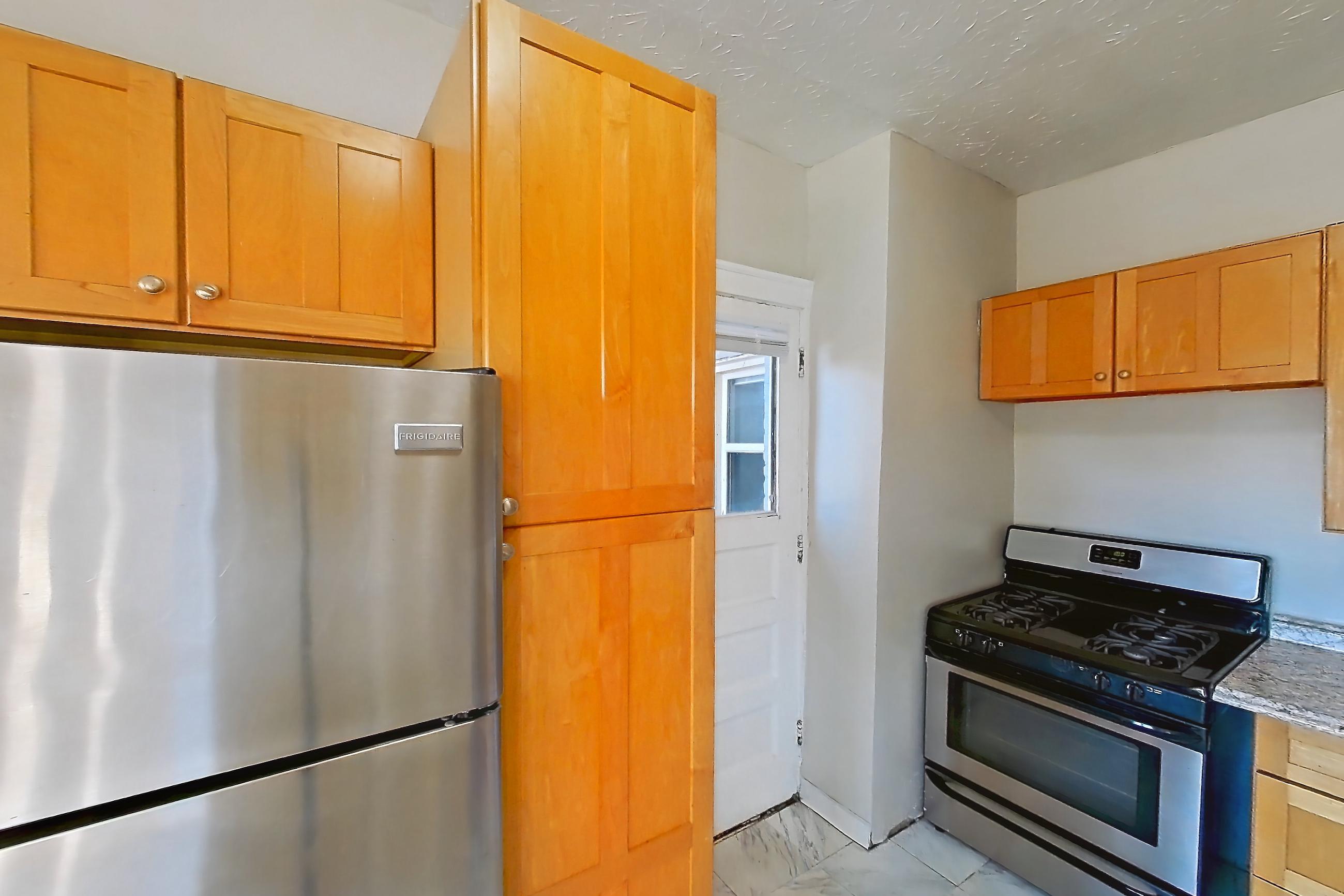 Kitchen with dishwasher, gas range, light countertops, light marble-finish flooring, light stone countertops, marble-look tile flooring, oven/range, refrigerator, and stainless steel appliances, Apartment 95-5 at Integrity Gold Coast